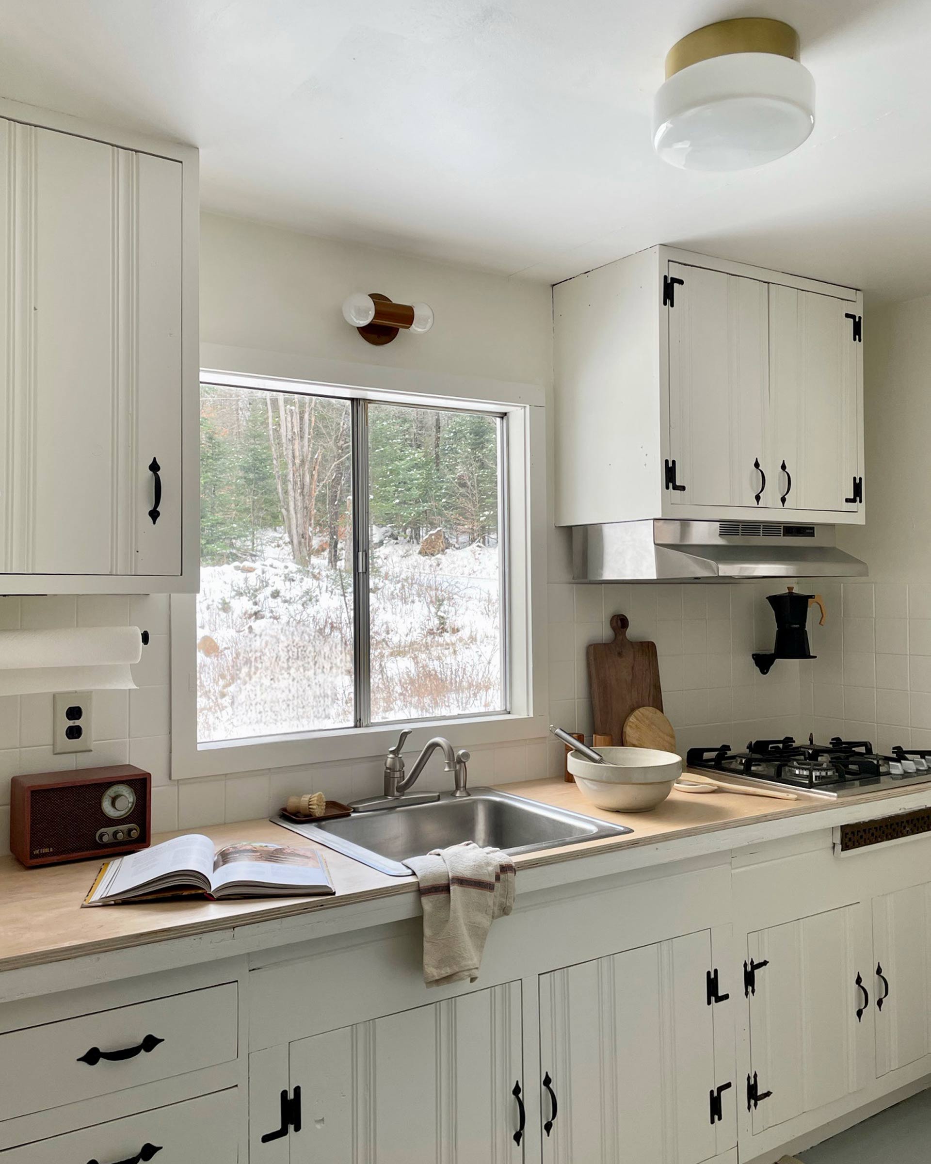 A double wall sconce over a window in a kitchen.