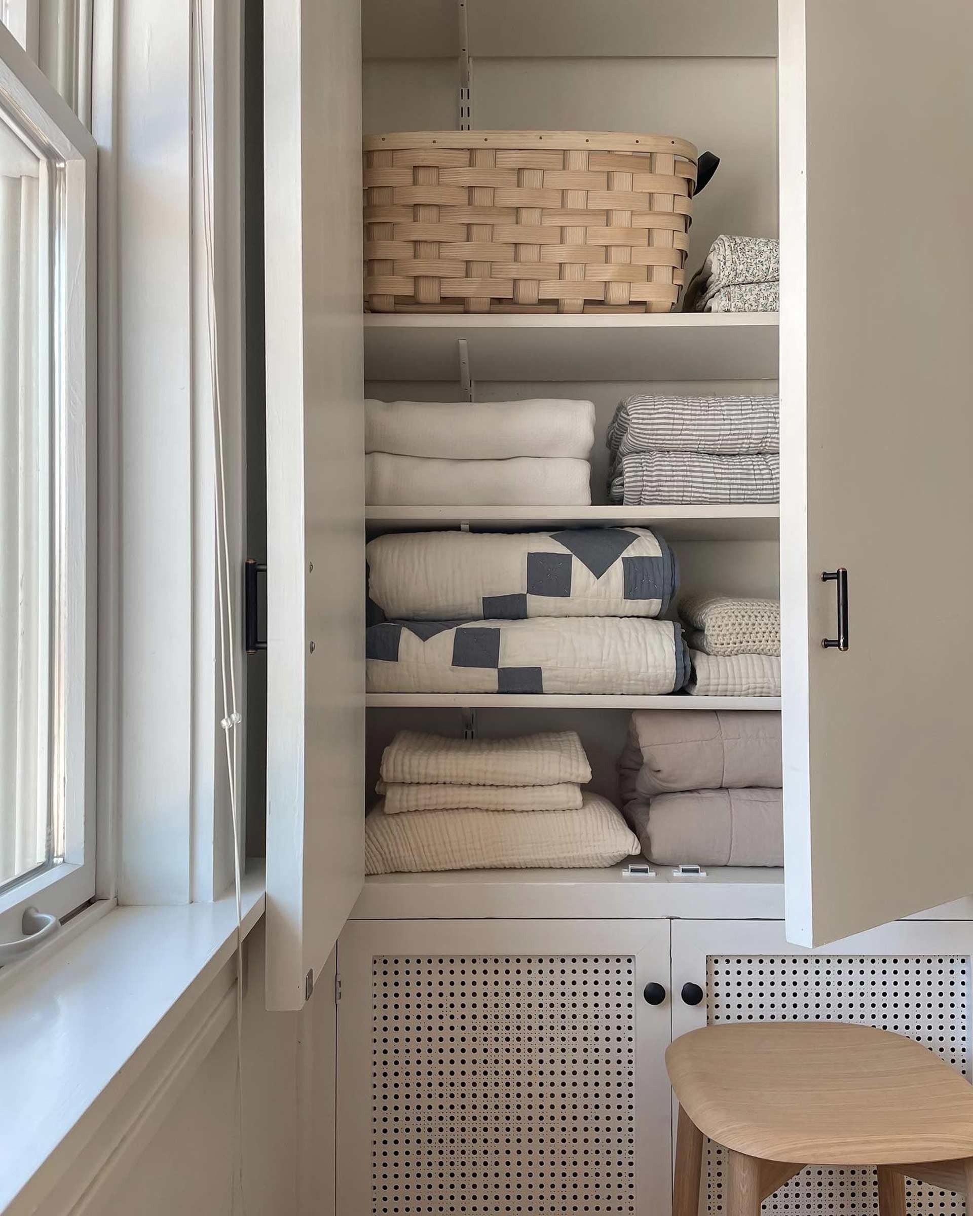 Well-organized linen closet with baskets and vintage quilts.