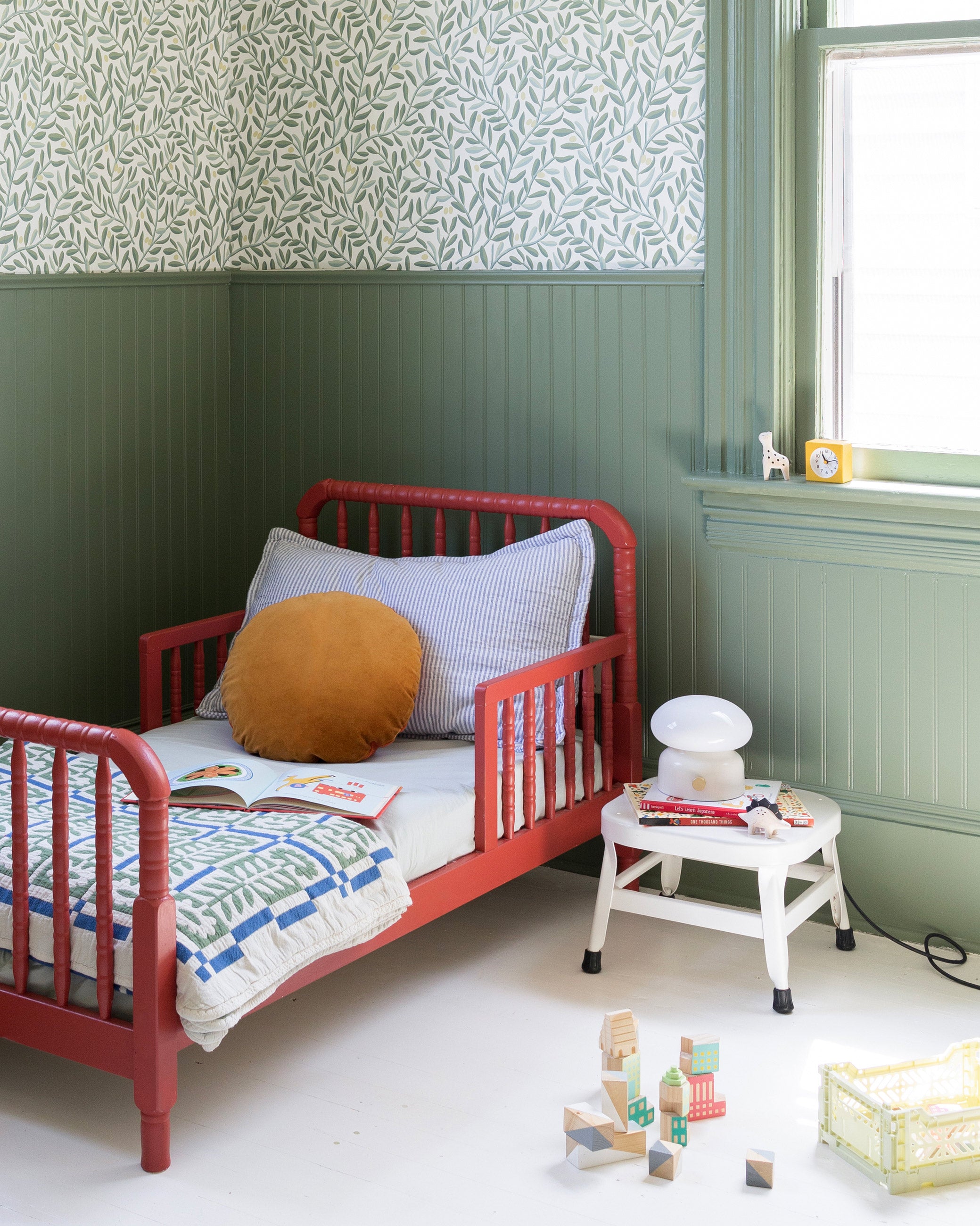 Child's bedroom with green walls and olive grove wallpaper. 