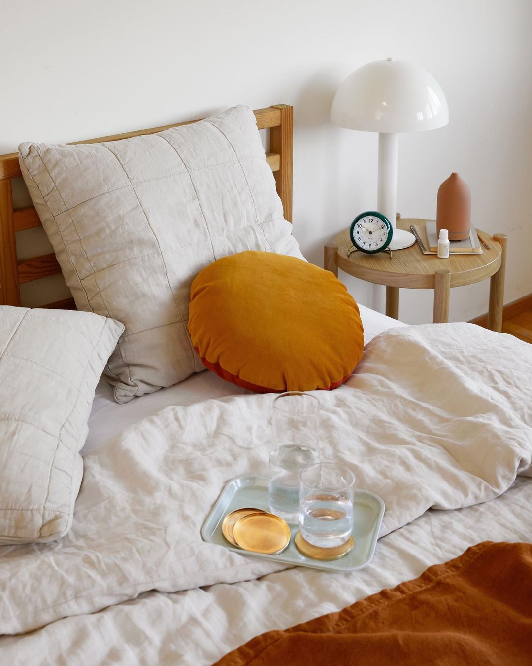 bed with a white pillow and a round table with glasses on it