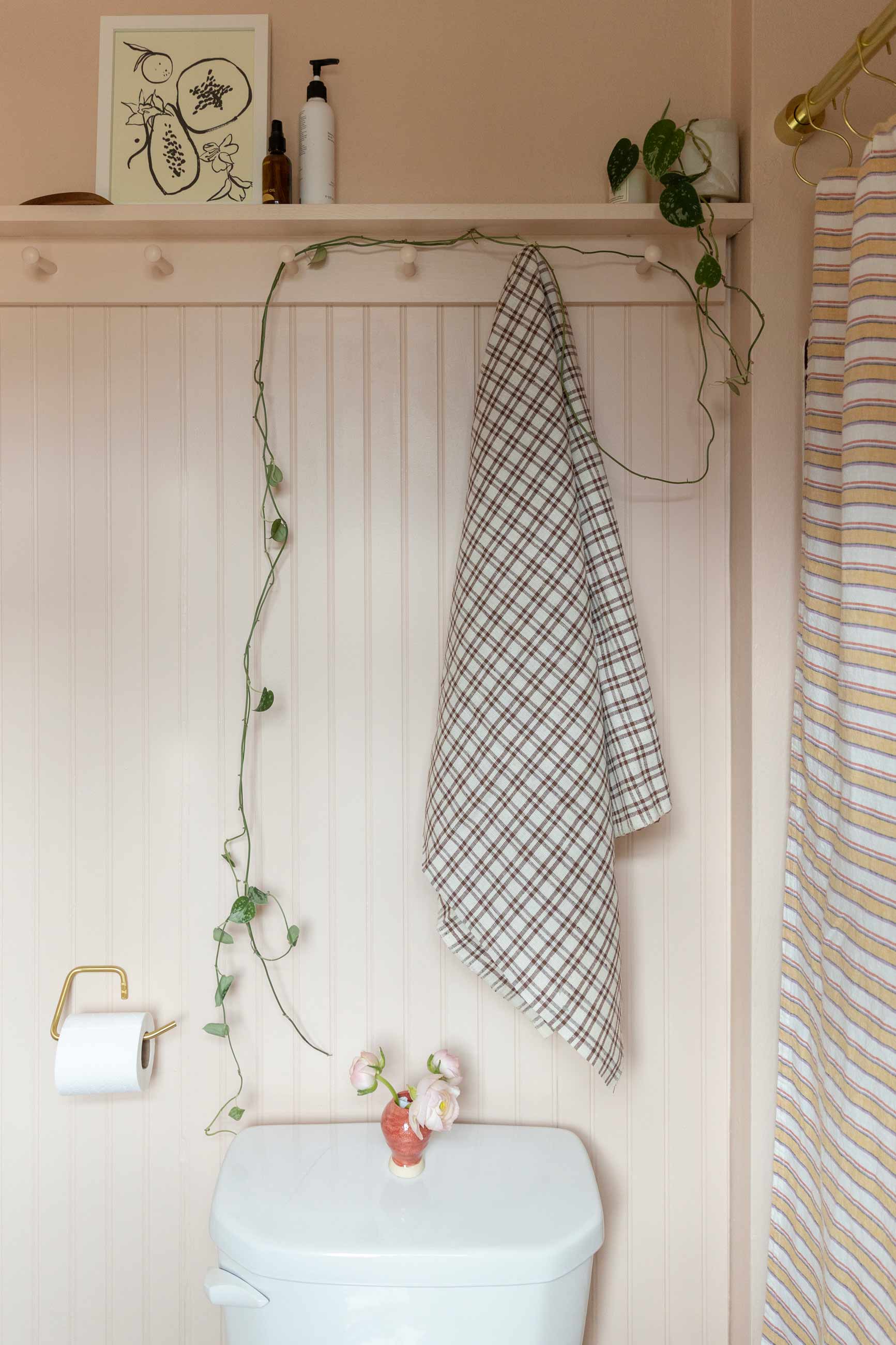 After image of pink beadboard wall in bathroom with towel hanging from shaker peg.