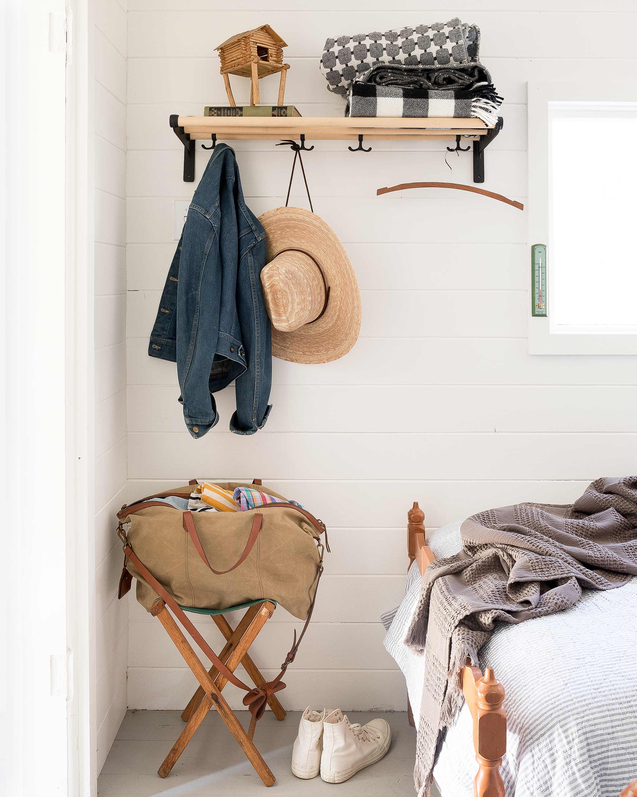 Shelf in bedroom to holding luggage, jackets, and a hat.
