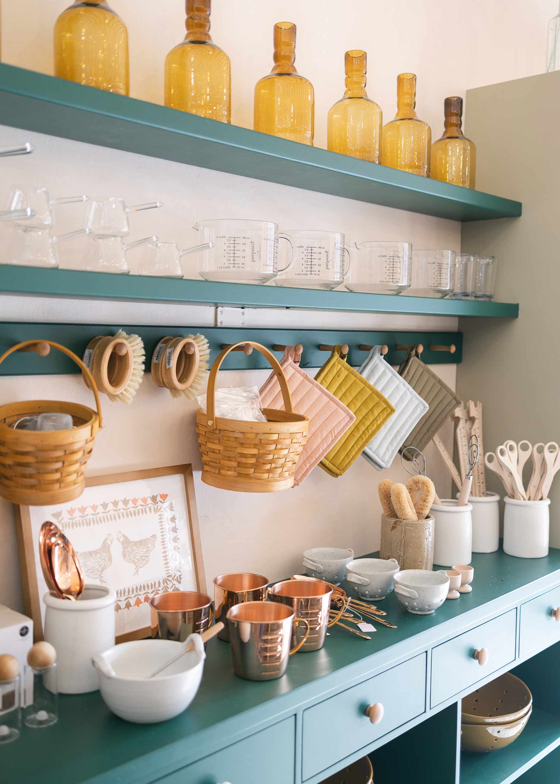 Teal shelf in store with kitchen supplies stacked on it. 