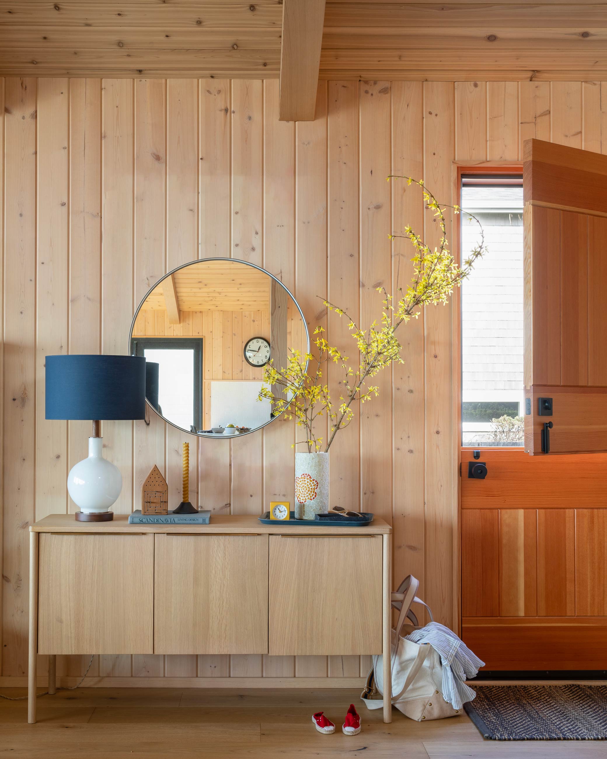 Large ceramic white lamp atop oak sideboard next to door. 