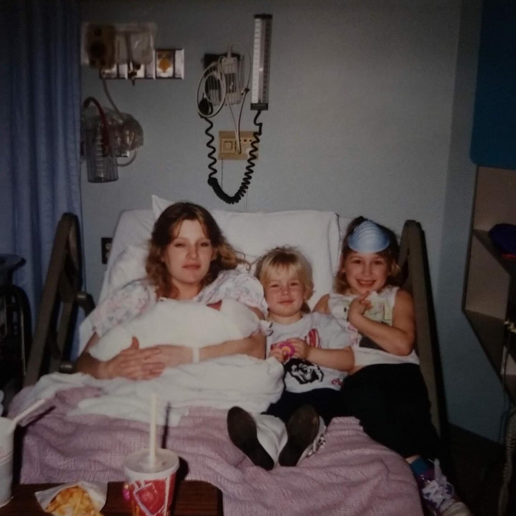 person holding an infant and two small children 