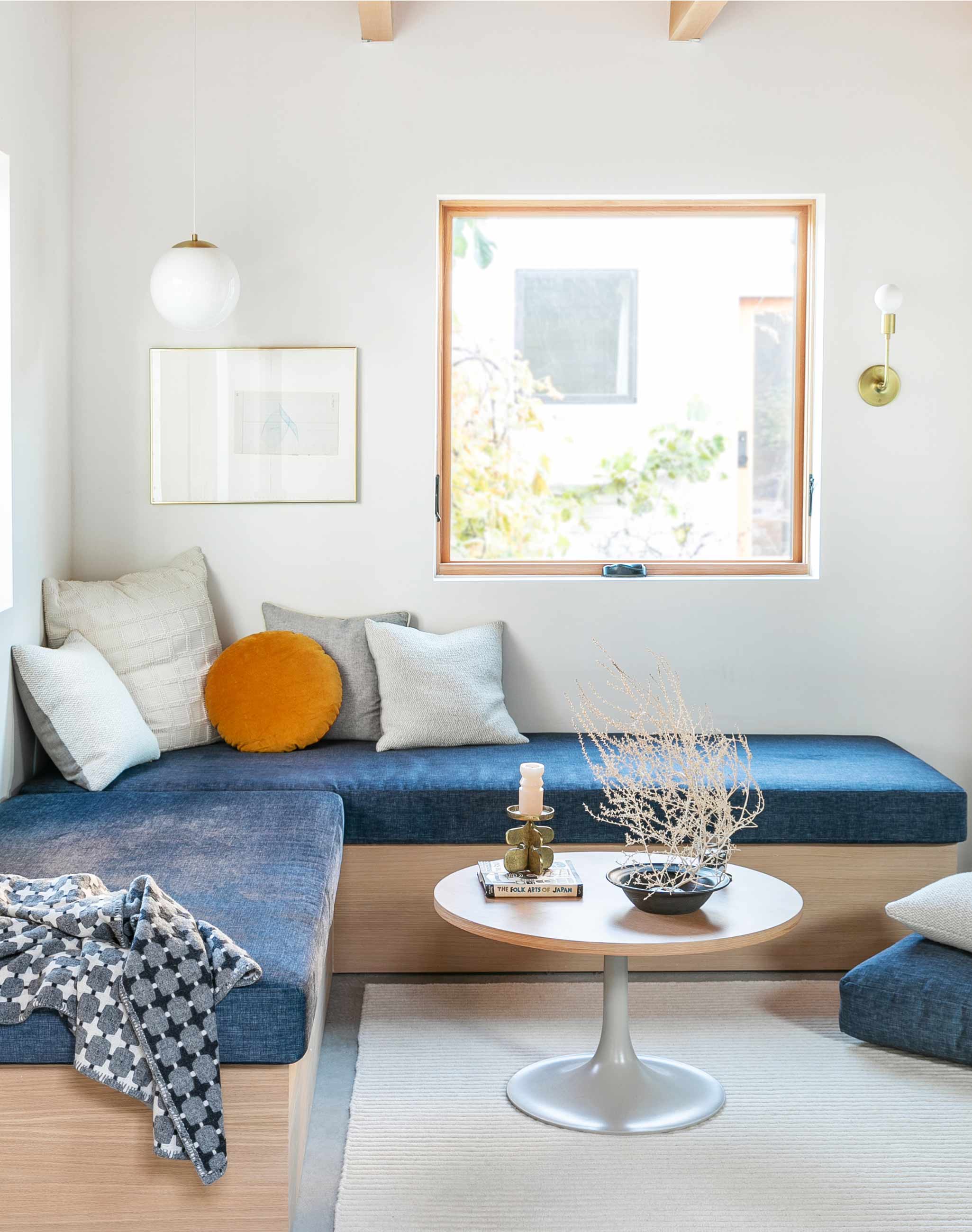 Bright and airy living room with blue couch and concrete floor. 