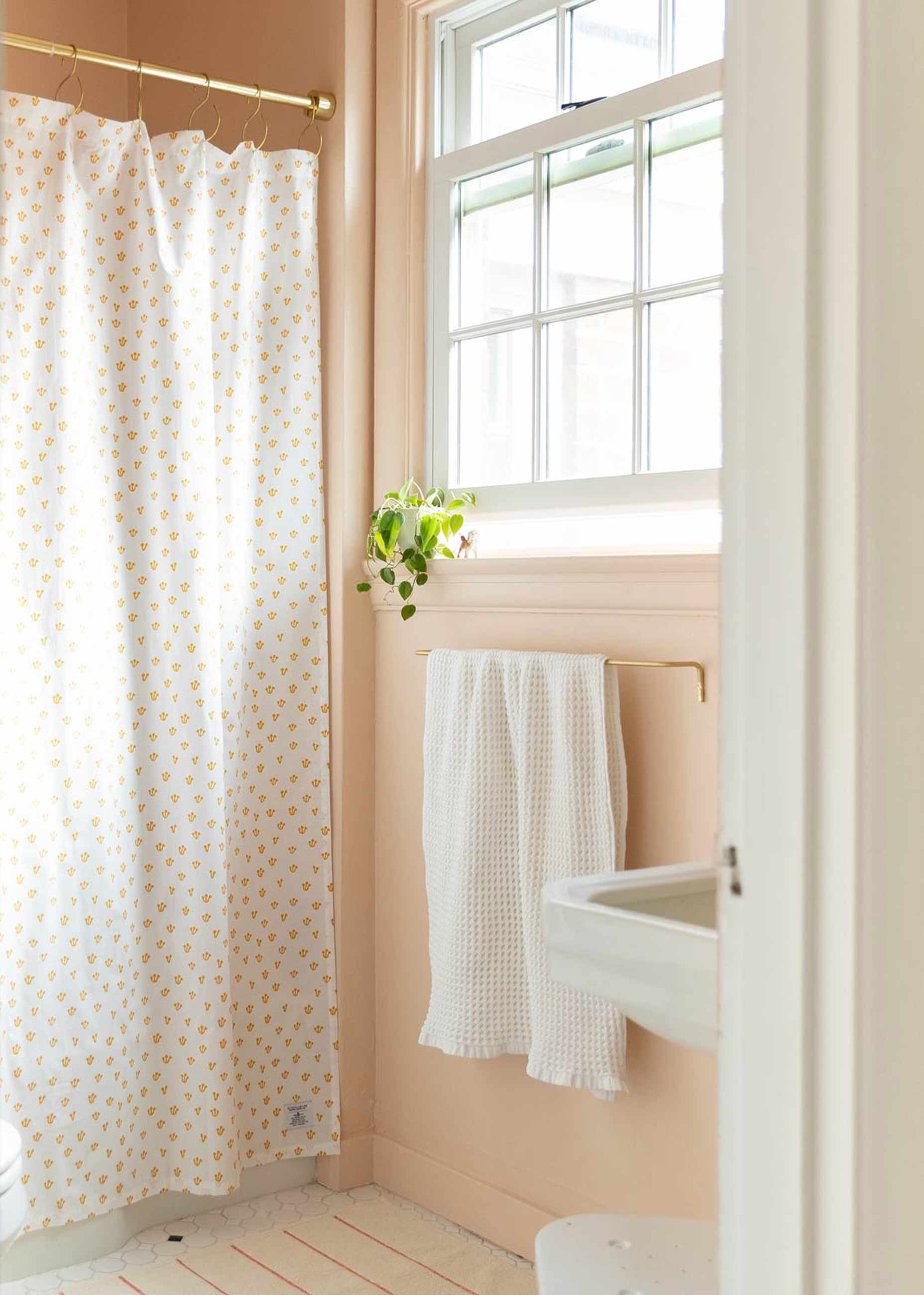 Bright pink bathroom with thistle shower curtain and striped bath mat.