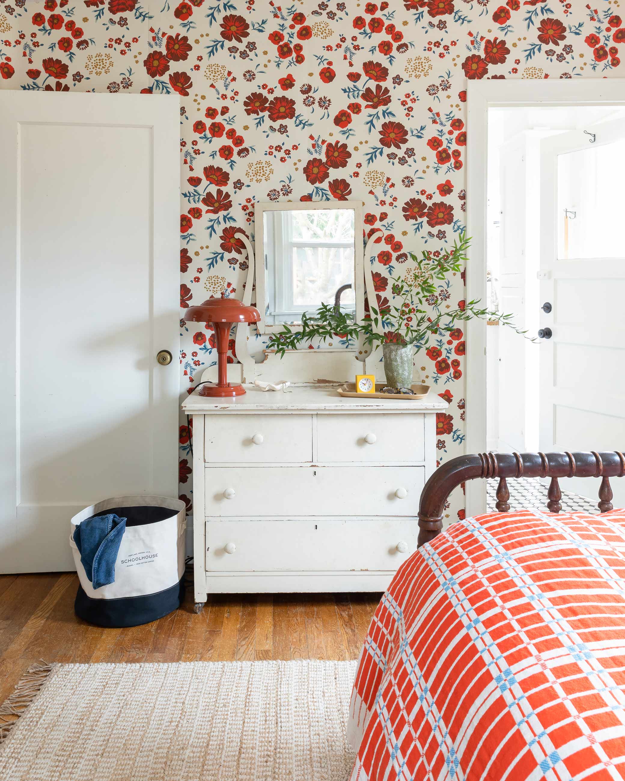 Brightly colored bedroom with red floral wallpaper and matching bedding.
