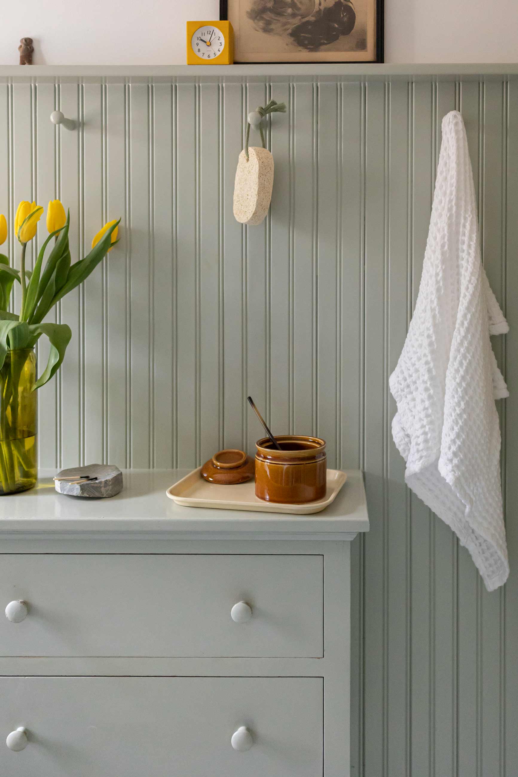 Built in bathroom cabinet with tulips in a vase on top. 