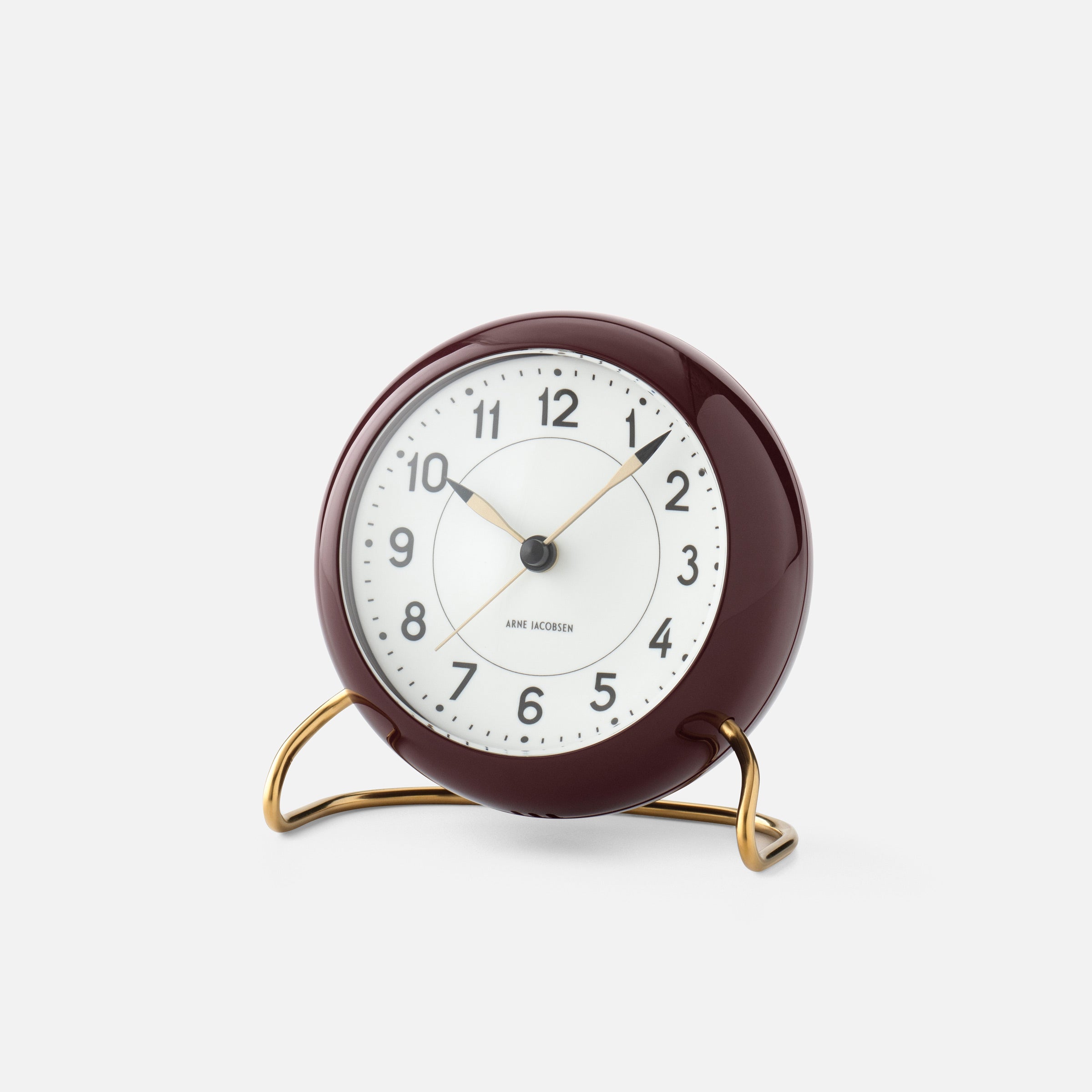 Burgundy Arne Jacobsen analog alarm clock with brass stand.