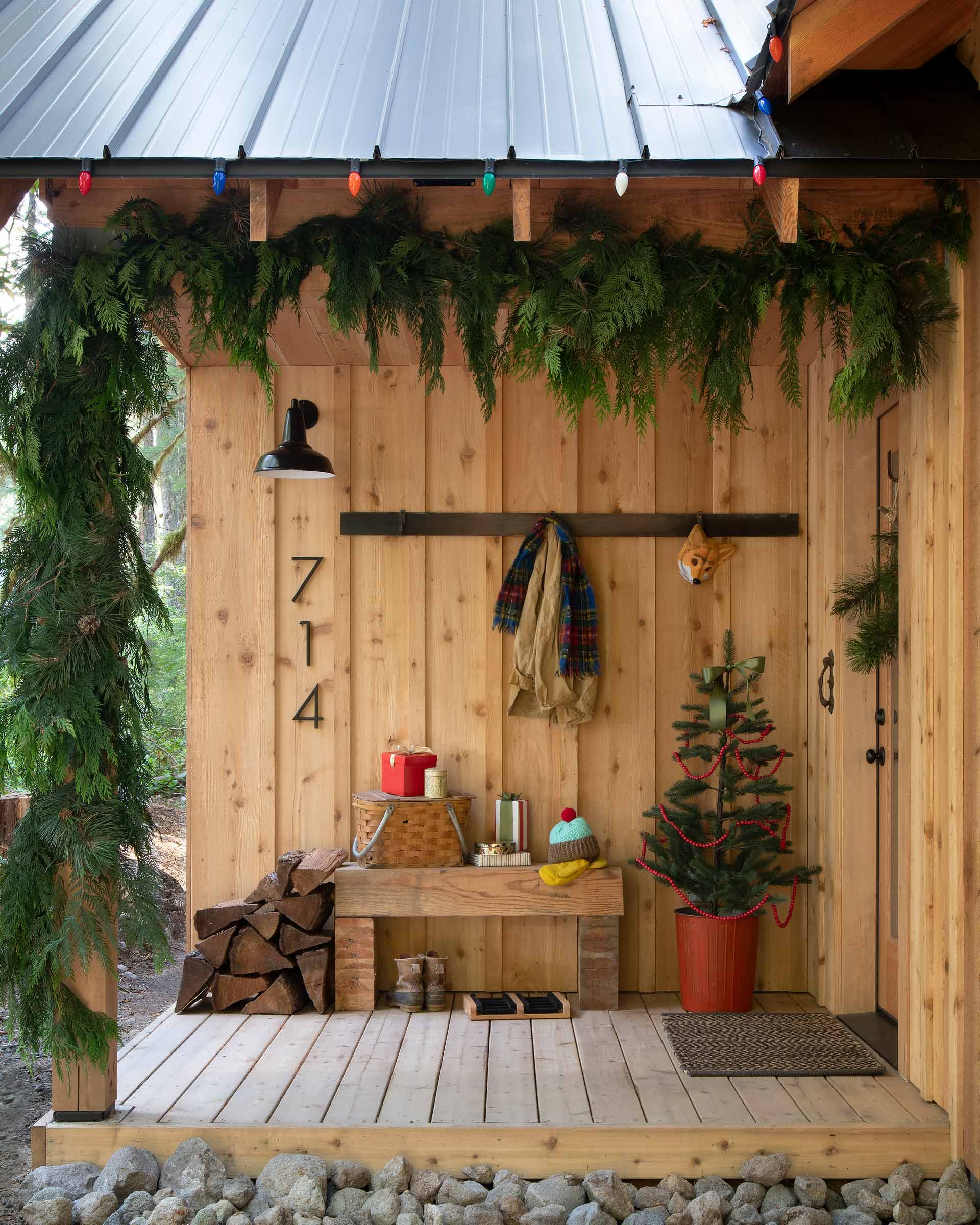 Cabin porch styled for the holiday with a tree and garland.