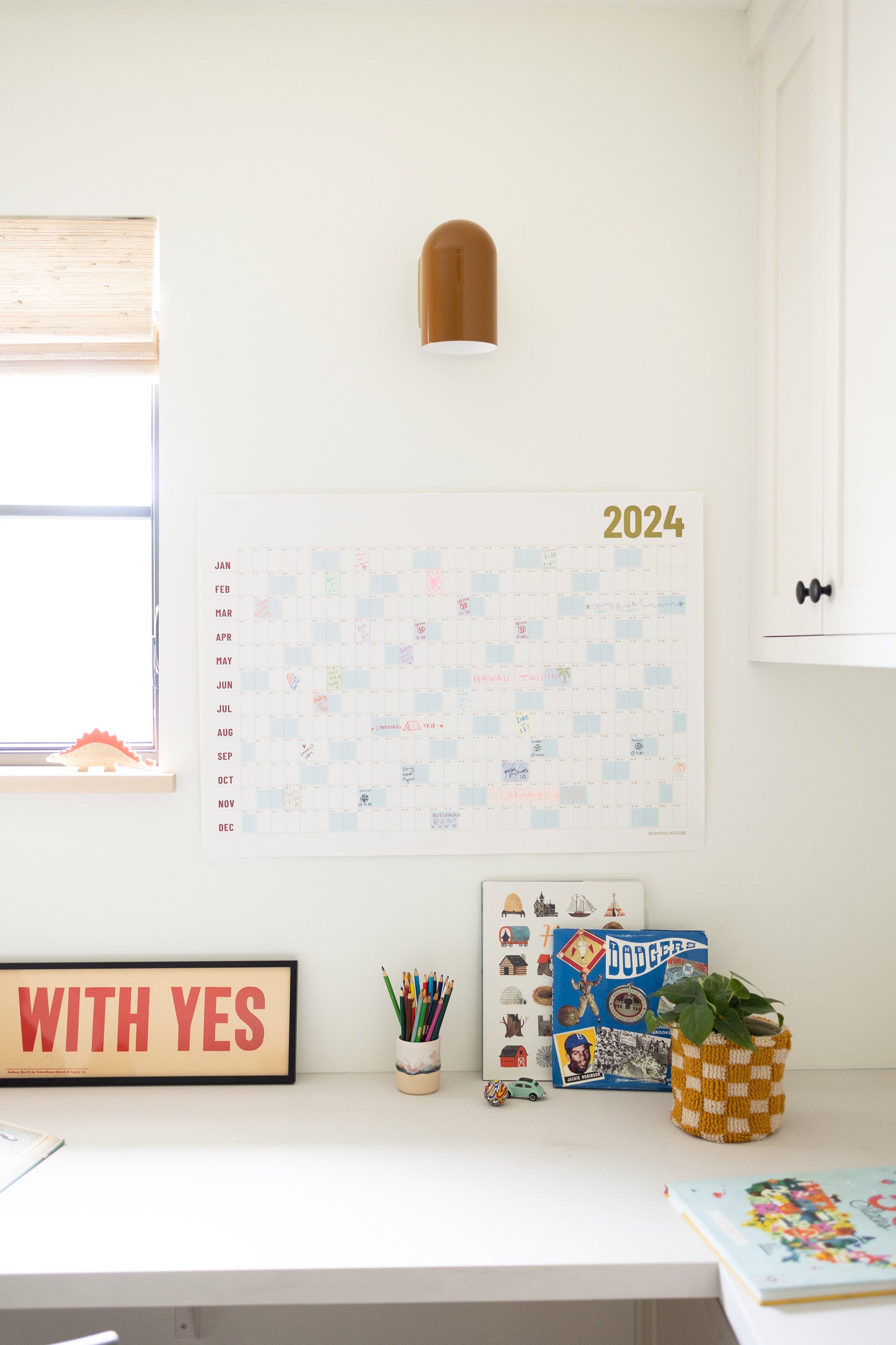 Calendar on wall above white desk. 