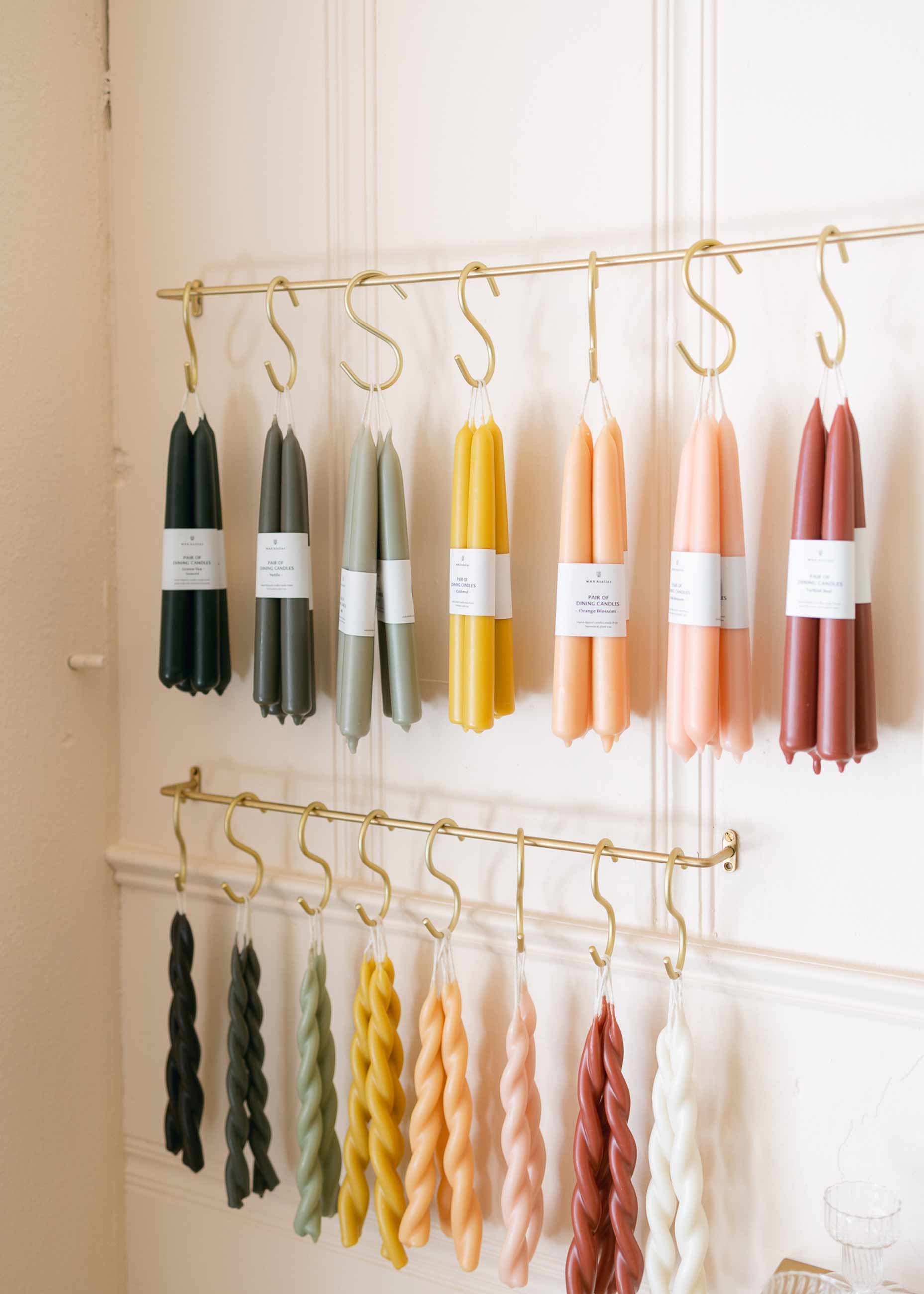 Colorful taper candles hanging on rack in a store. 