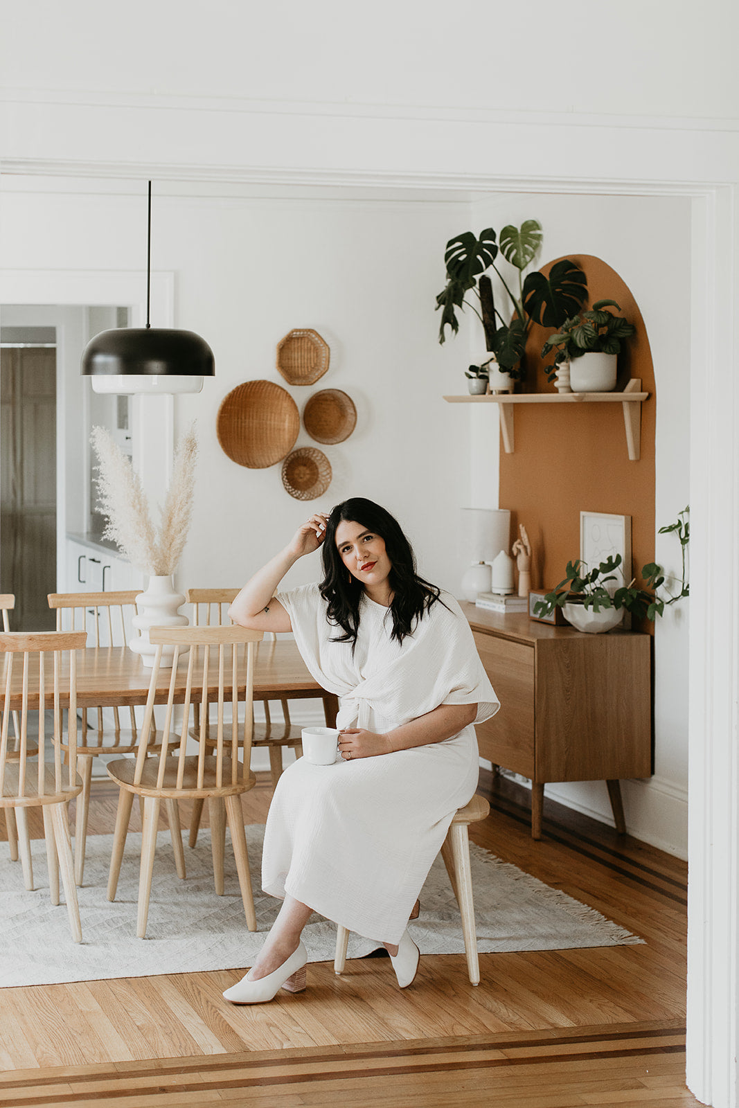 person in a white dress sitting on a chair in a diningroom