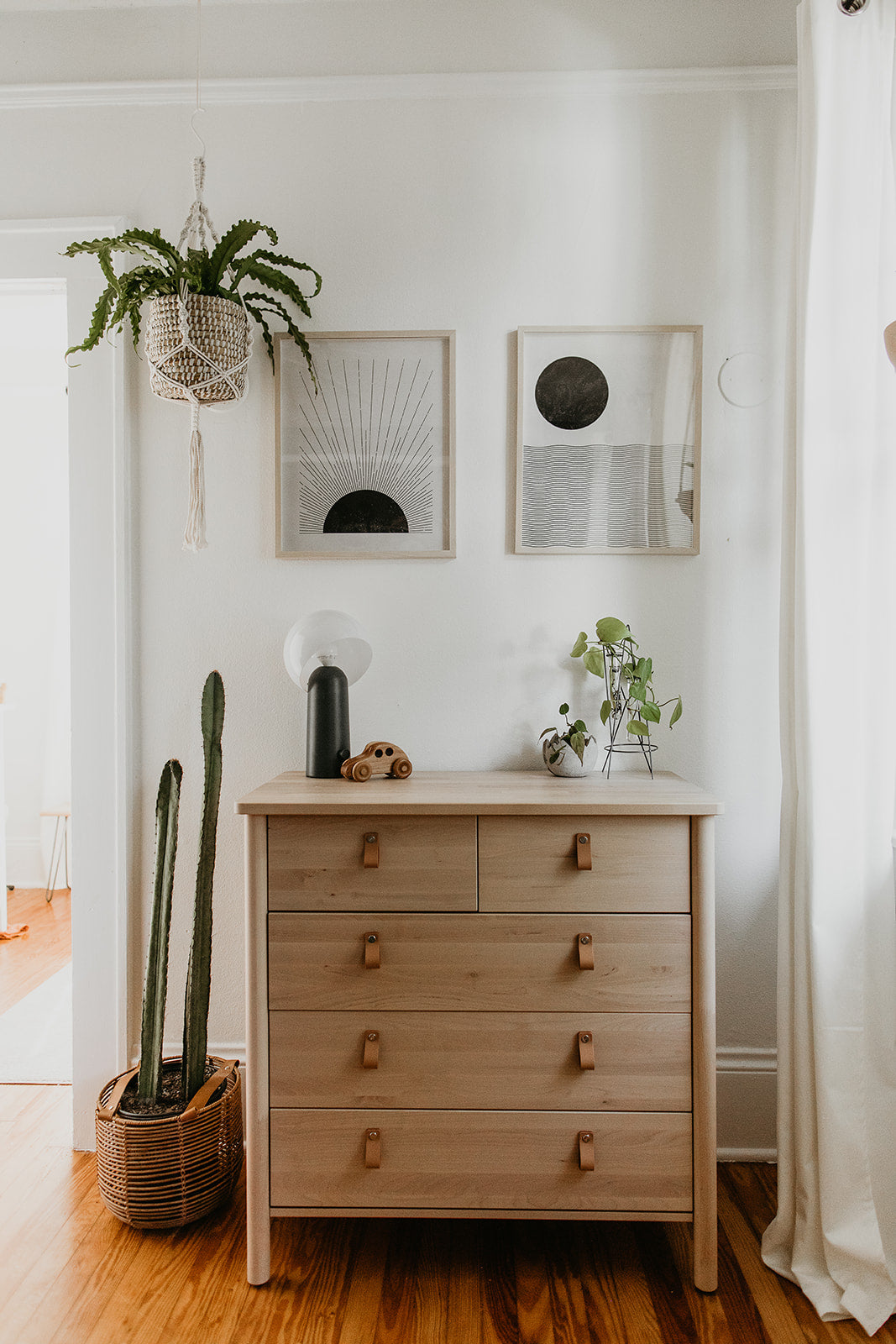 dresser with a plant on top and artwork