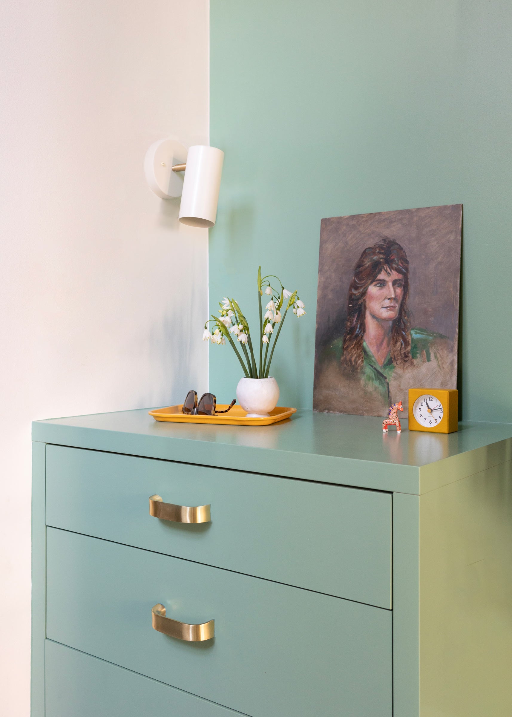 A spruce green cabinet corner and accent wall with brass cabinet pulls. 