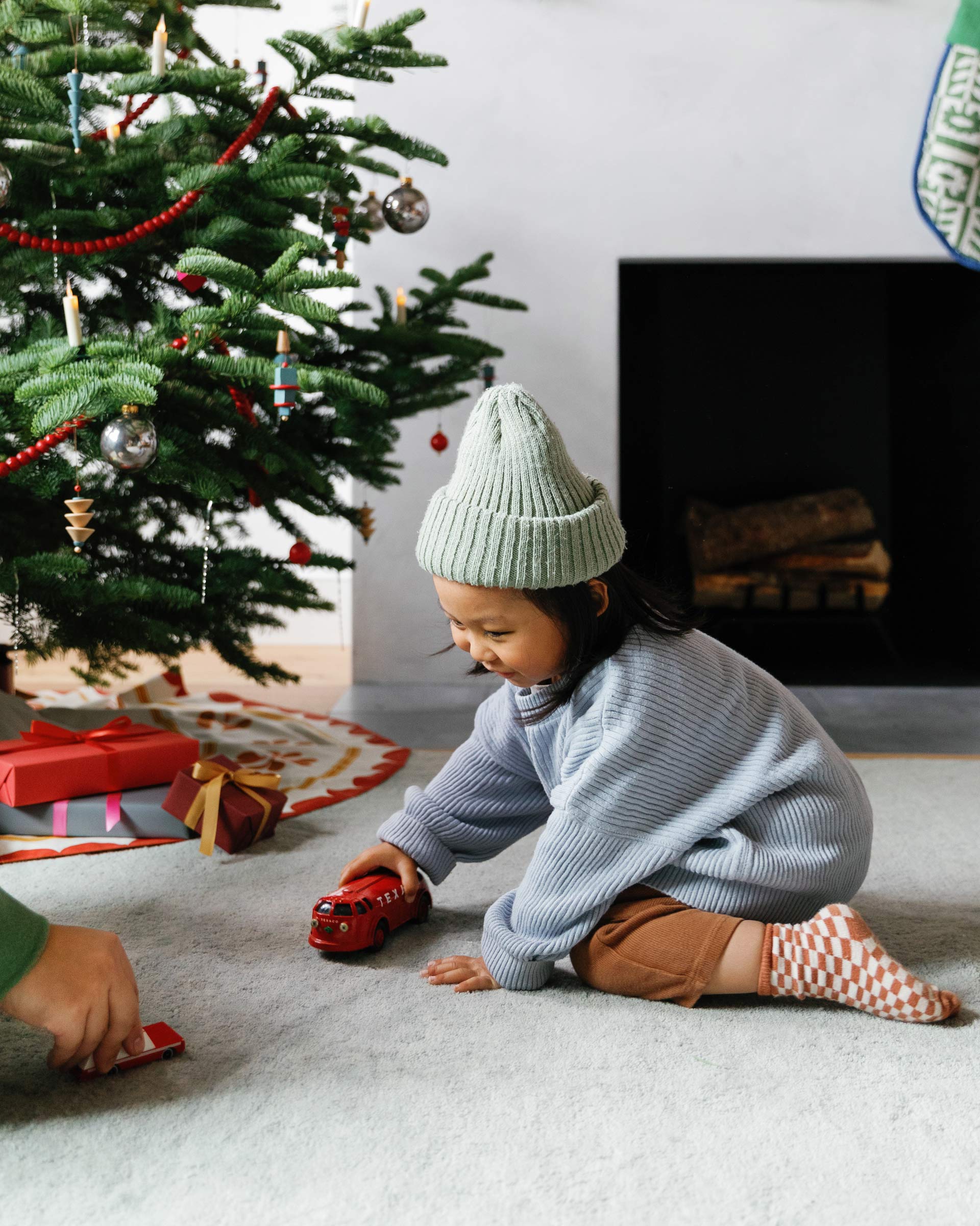 Child playing by a Christmas tree.