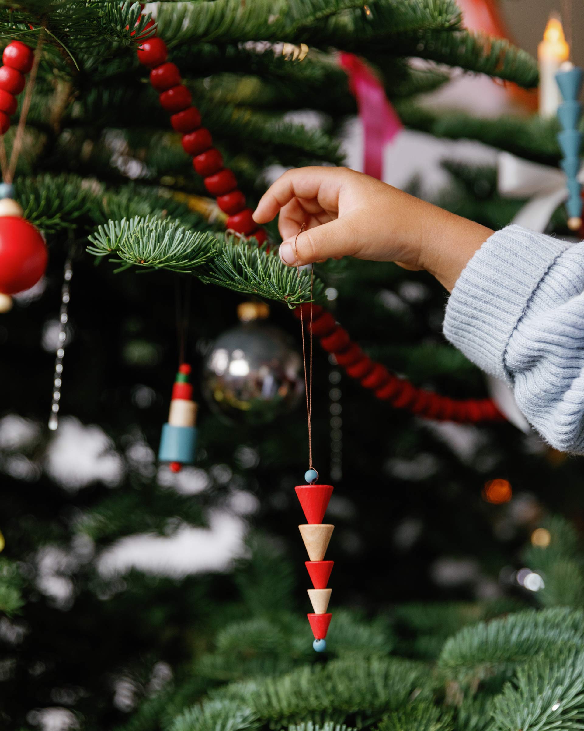 Child putting ornament on tree.