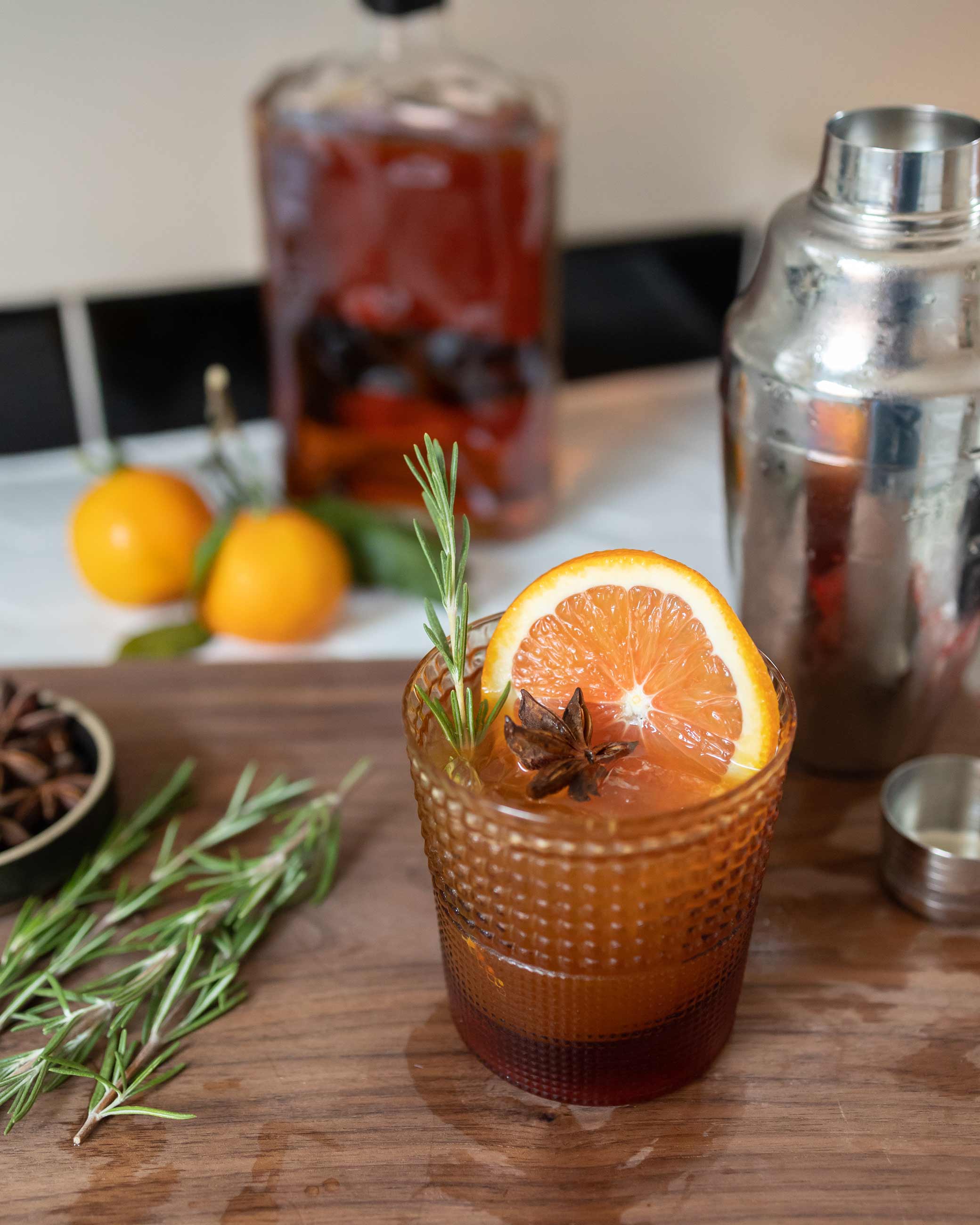 Festive holiday cocktail in textured lowball glass on wood cutting board.