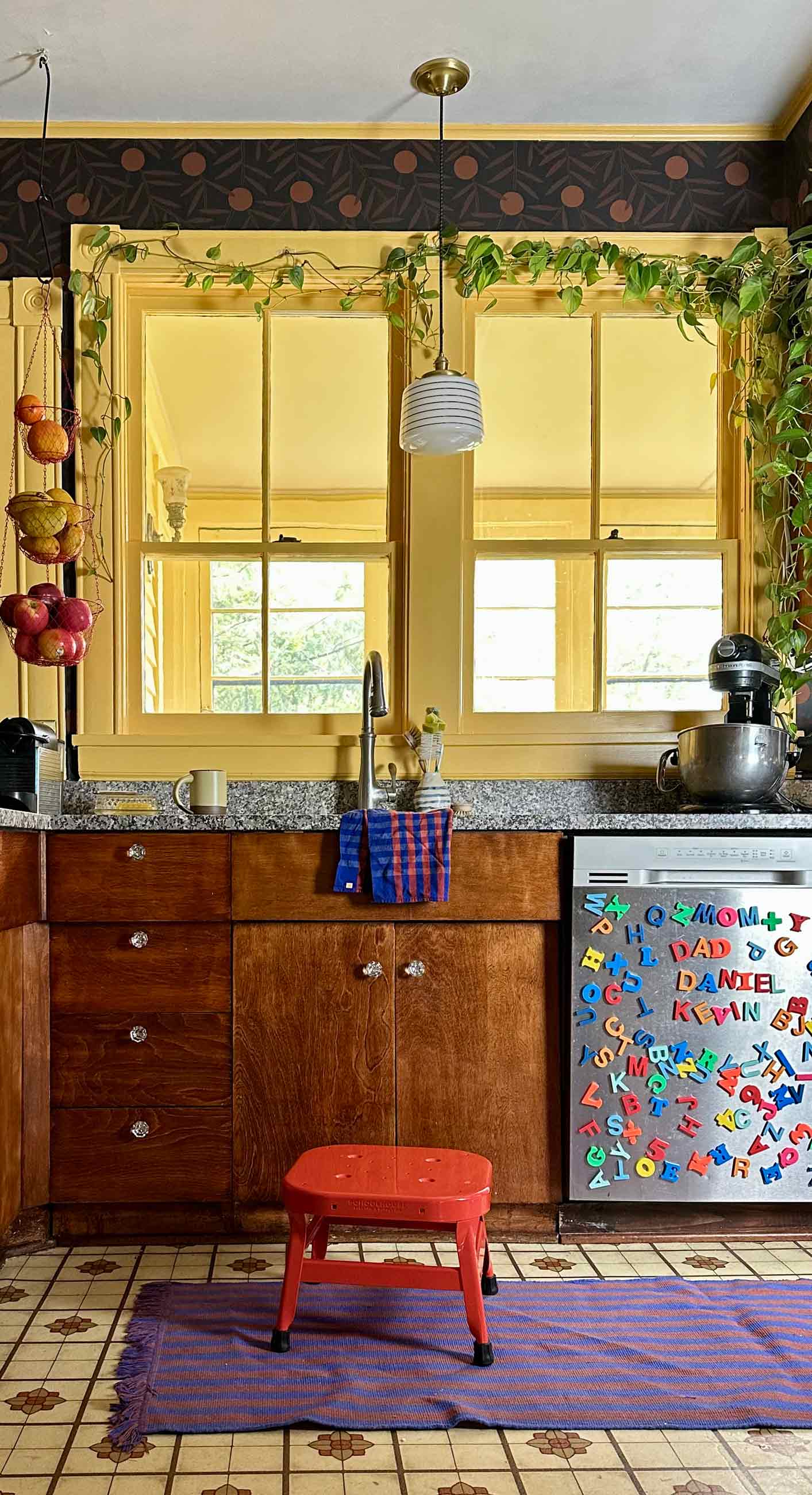 Colorful kitchen with red stool in front of sink.