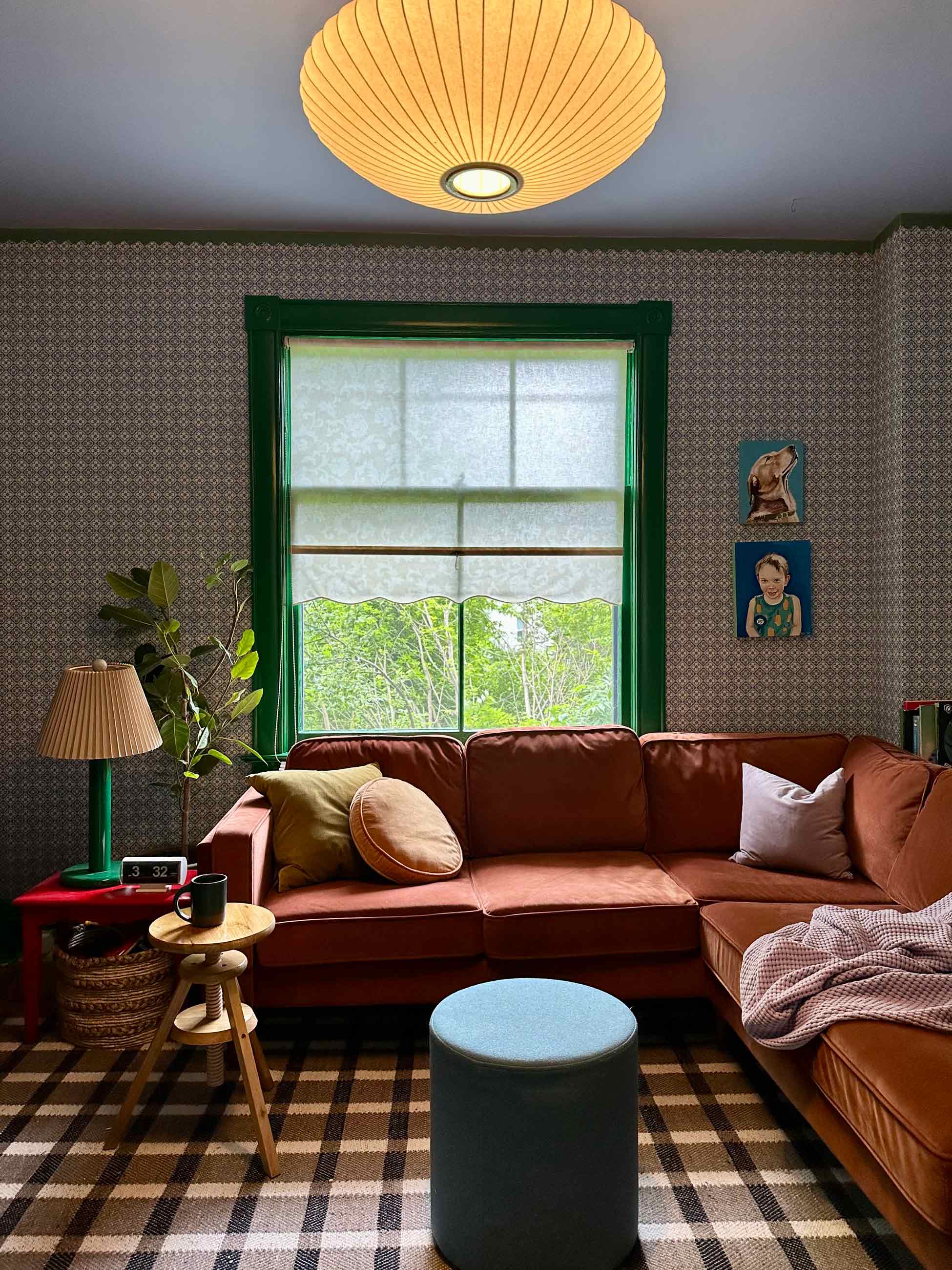 Colorful living room with wallpapered walls, green trim, and an orange sofa.