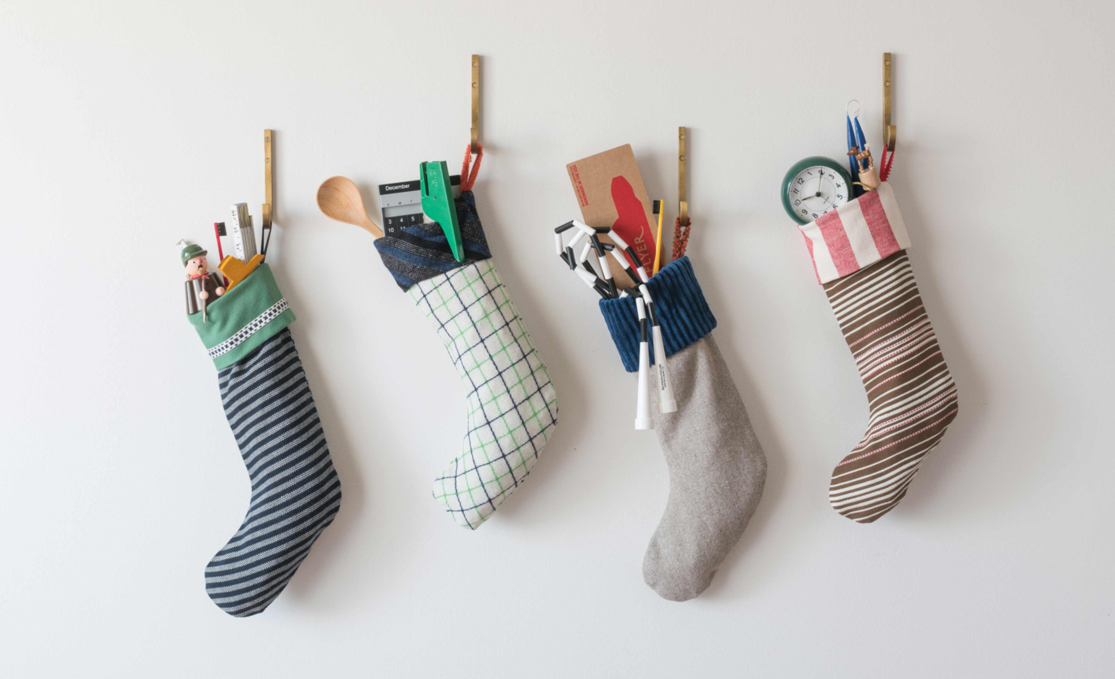 Four colorful stockings full of goodies hanging on gold hooks on a wall