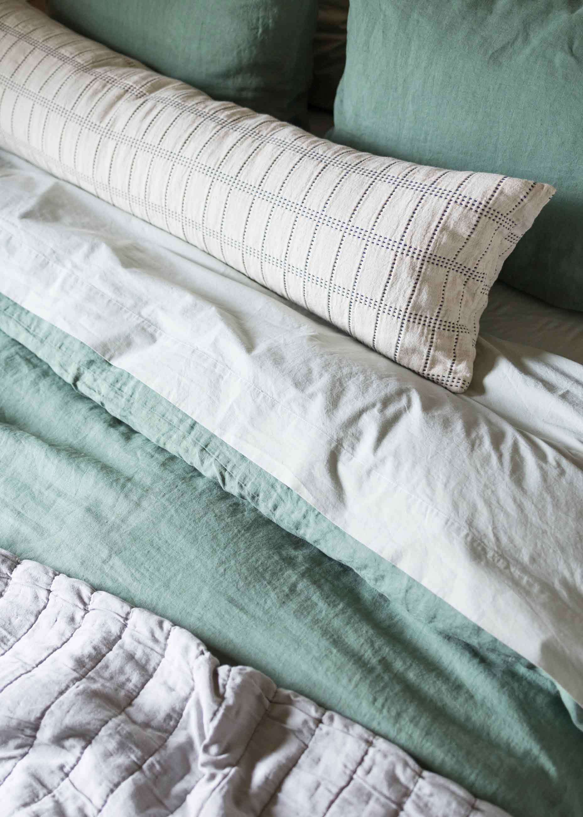 Up close shot of cozy neutral bedding on bed. 