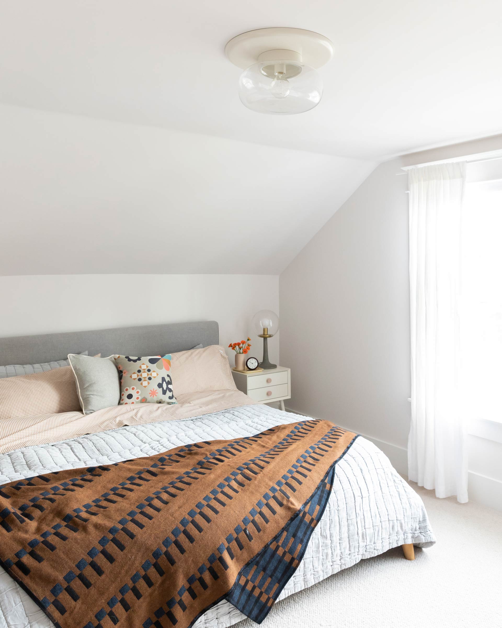 Bright bedroom with an Eleanor Pritchard throw blanket and cozy bedding.