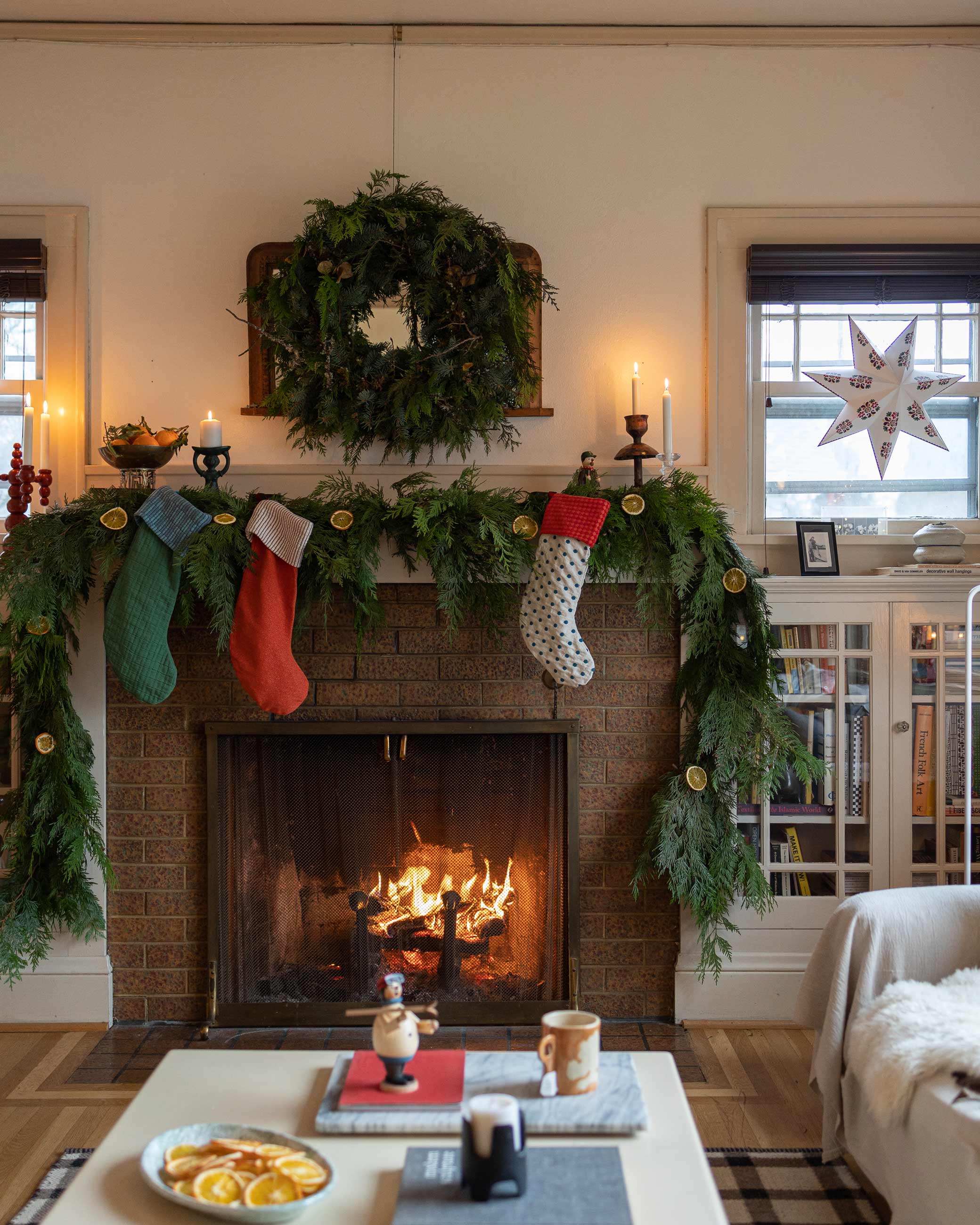 Cozy winter fireplace with colorful stockings and bushy garland on mantel.