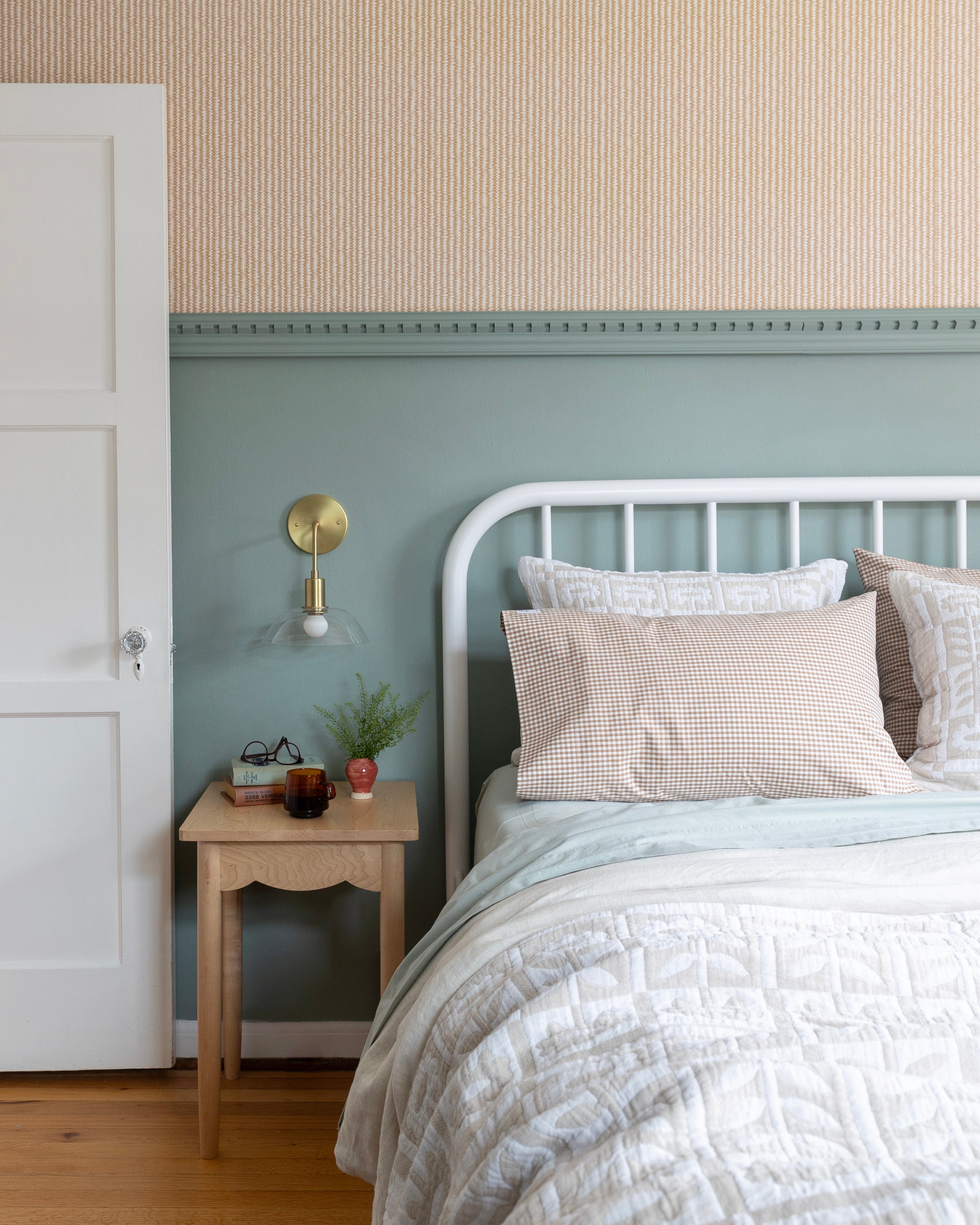 Cozy bed in blue bedroom with wallpaper.