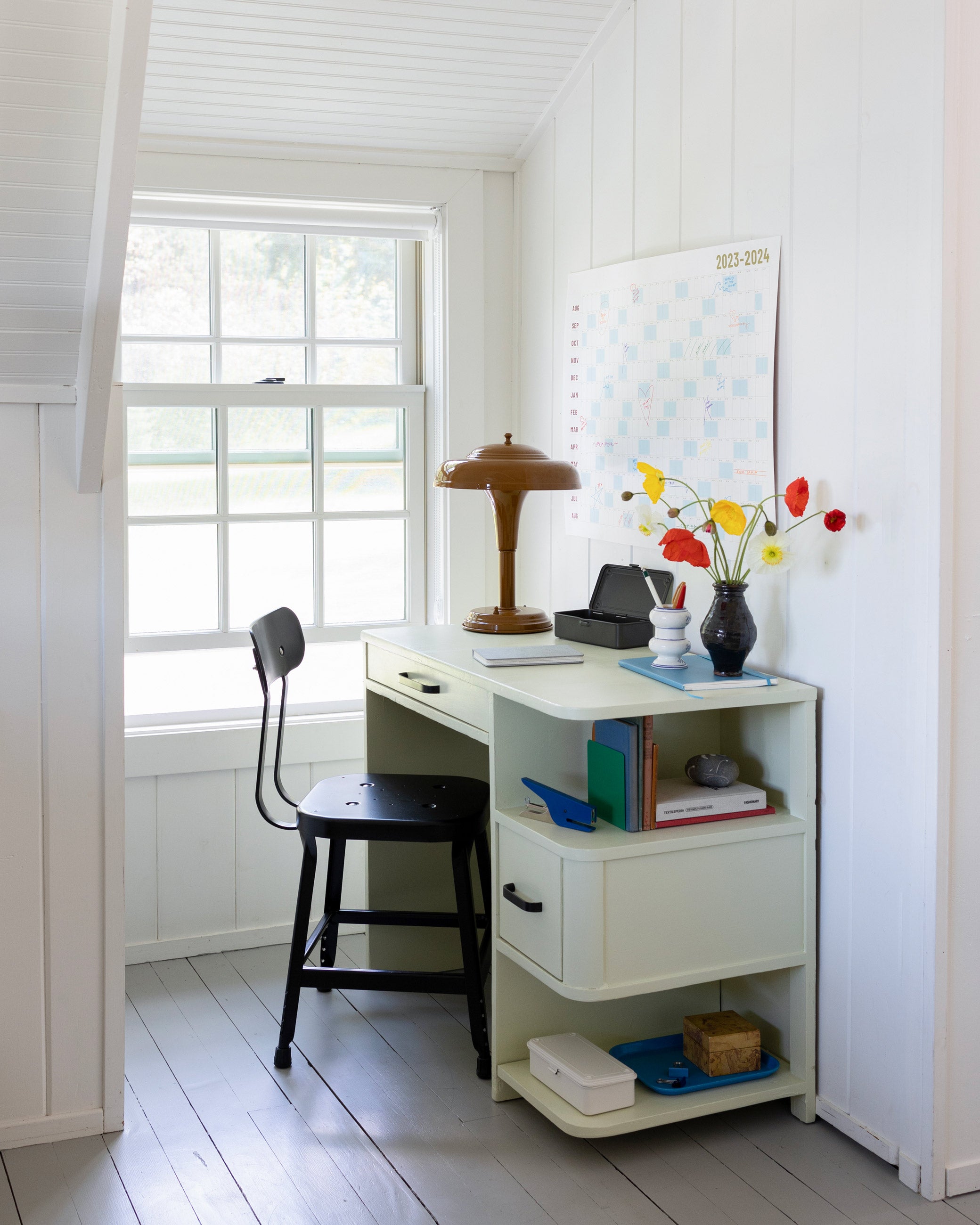 White desk with large calendar hanging above it. 