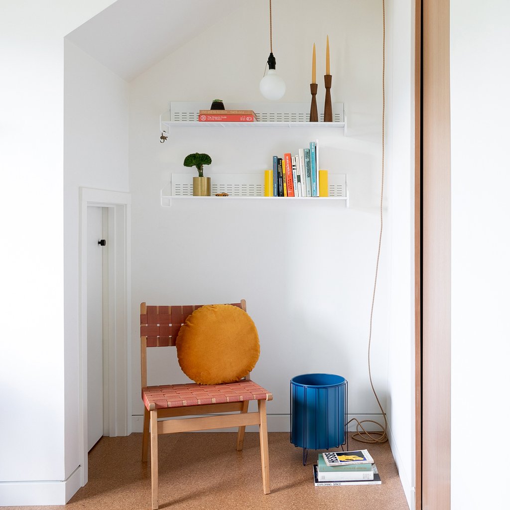 chair in a room with yellow round pillow and shelves on the wall