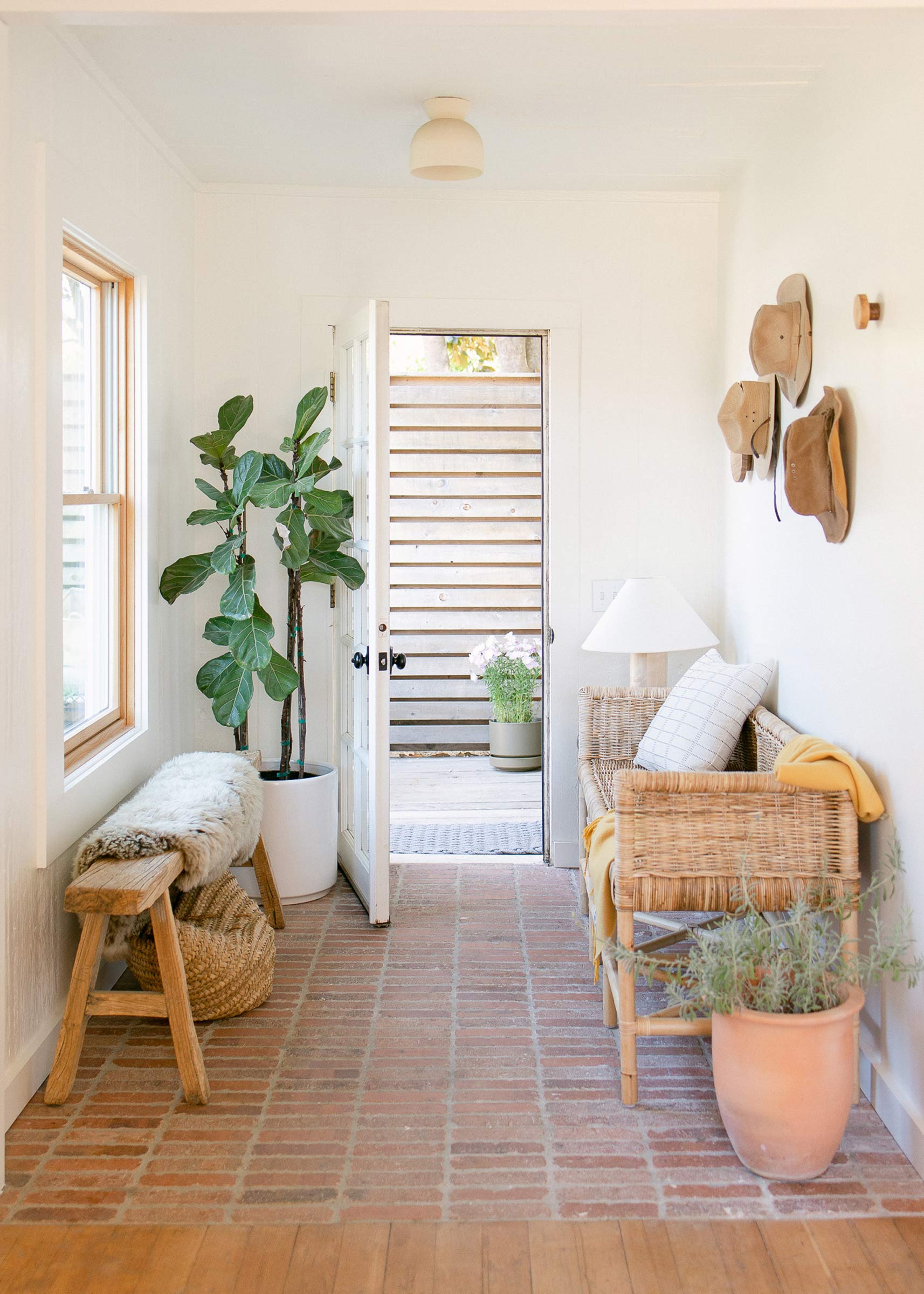 A bright entryway with brick floor, a ceramic surface mount, and small sitting area near the entrance.