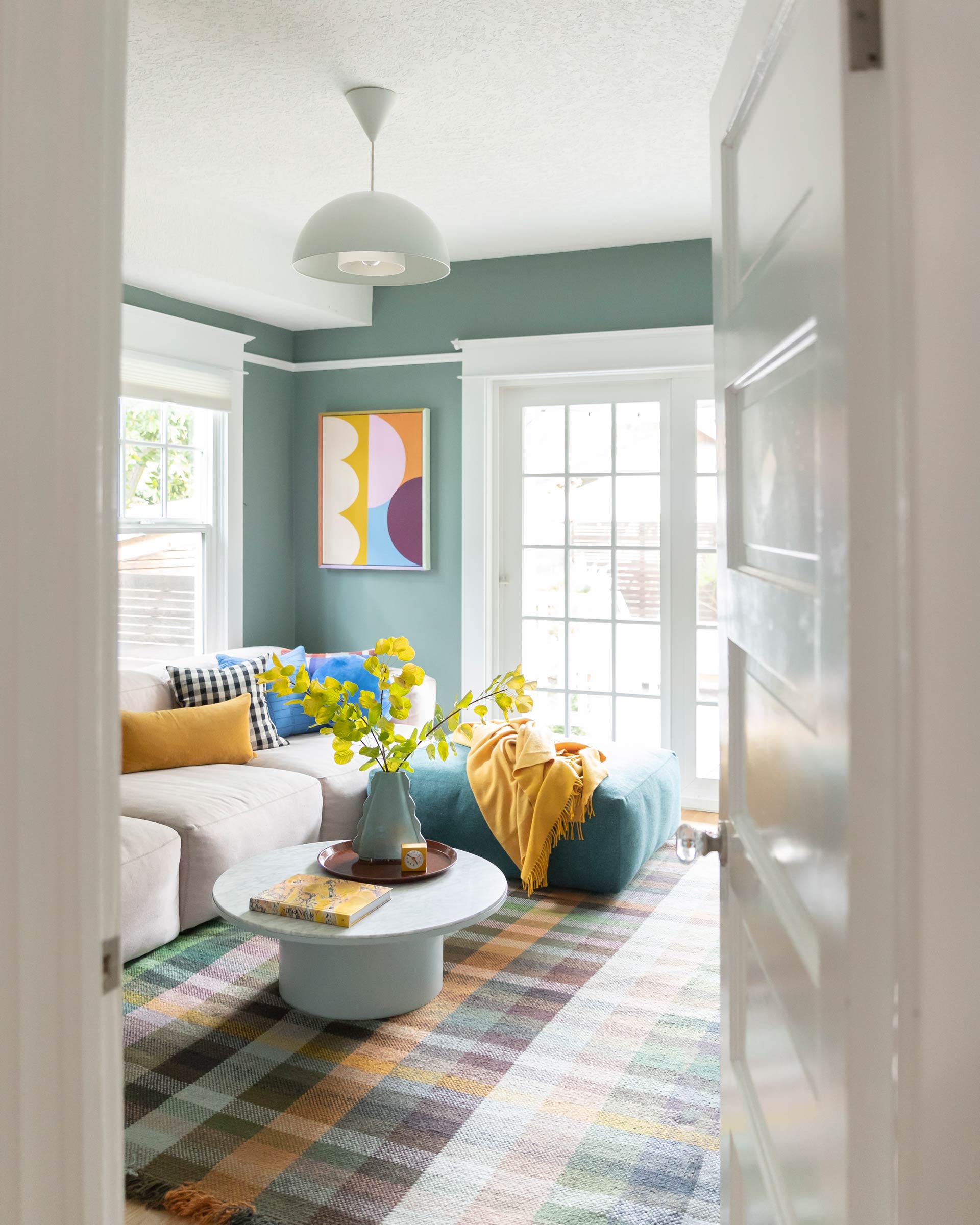 Modern family room with colorful art, rugs, and throw pillows.