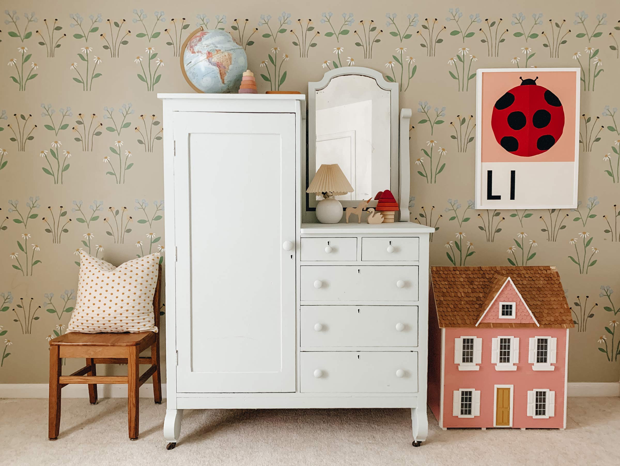 Hand-painted floral wallpaper in a kid's room with a pink dollhouse. 