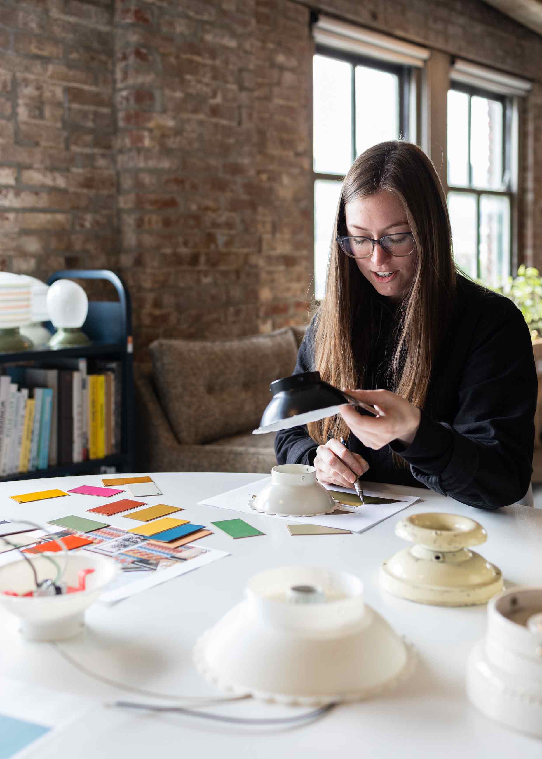 Person sitting at table working on light fixture design concepts.