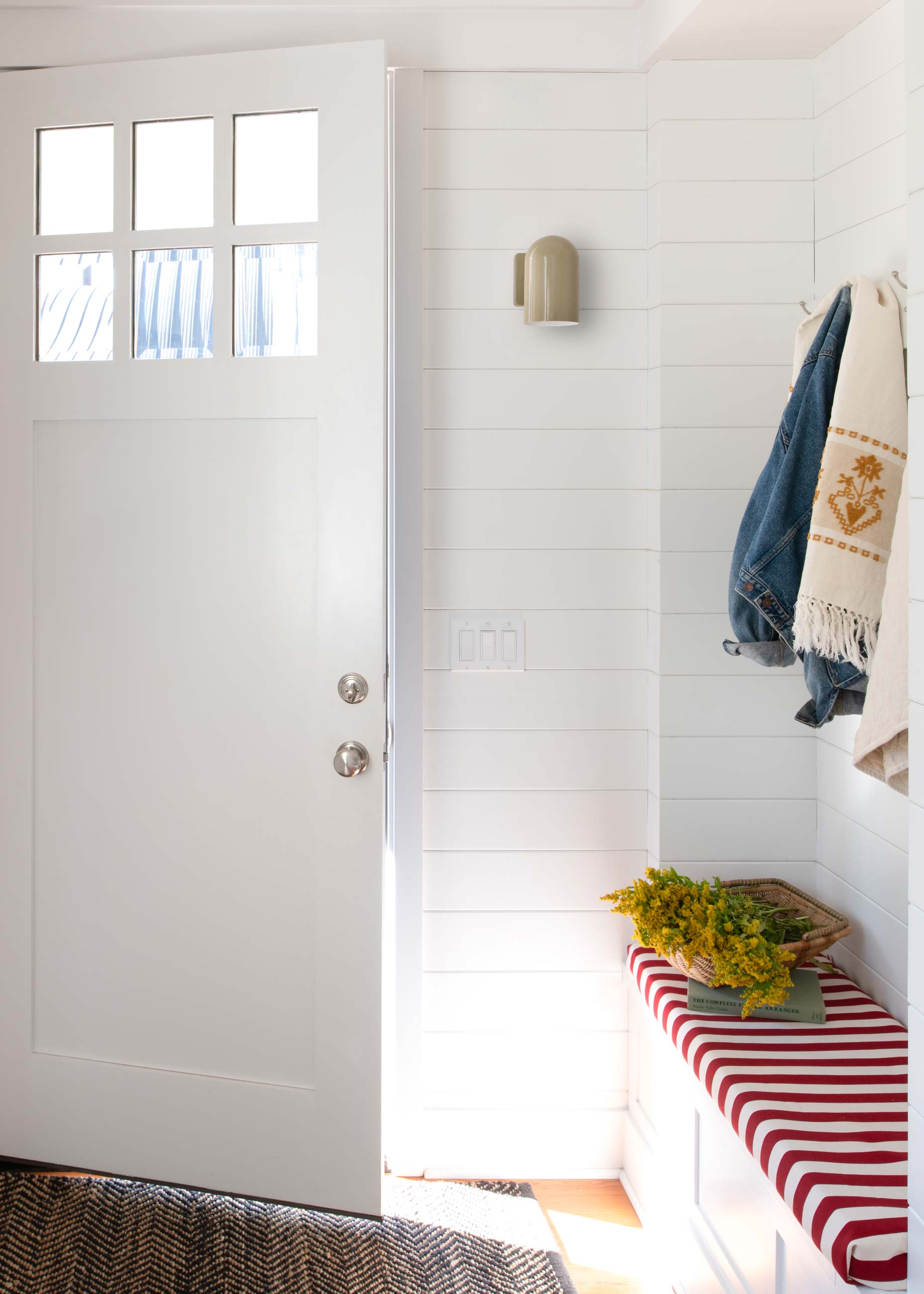 Bright and airy front entryway with red and white striped bench seating. 