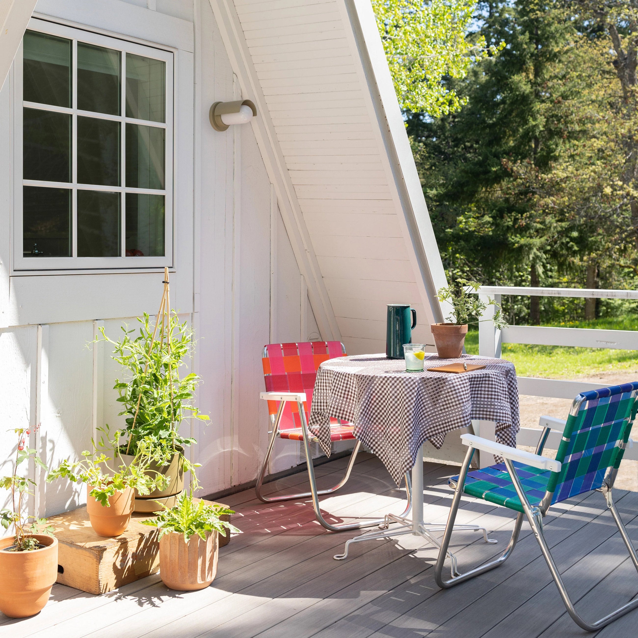 Front porch with table and brightly colored folding chairs.