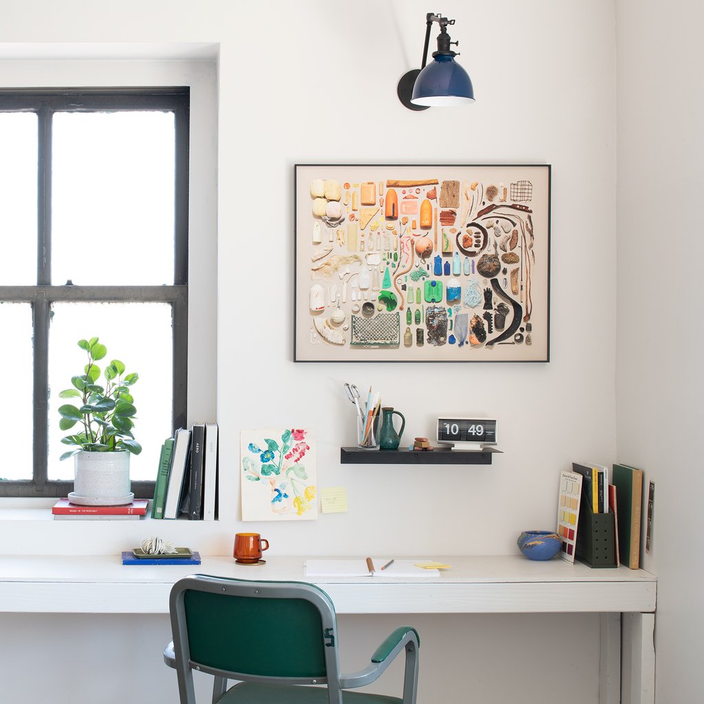 desk with a sconce and a picture on the wall next to the window