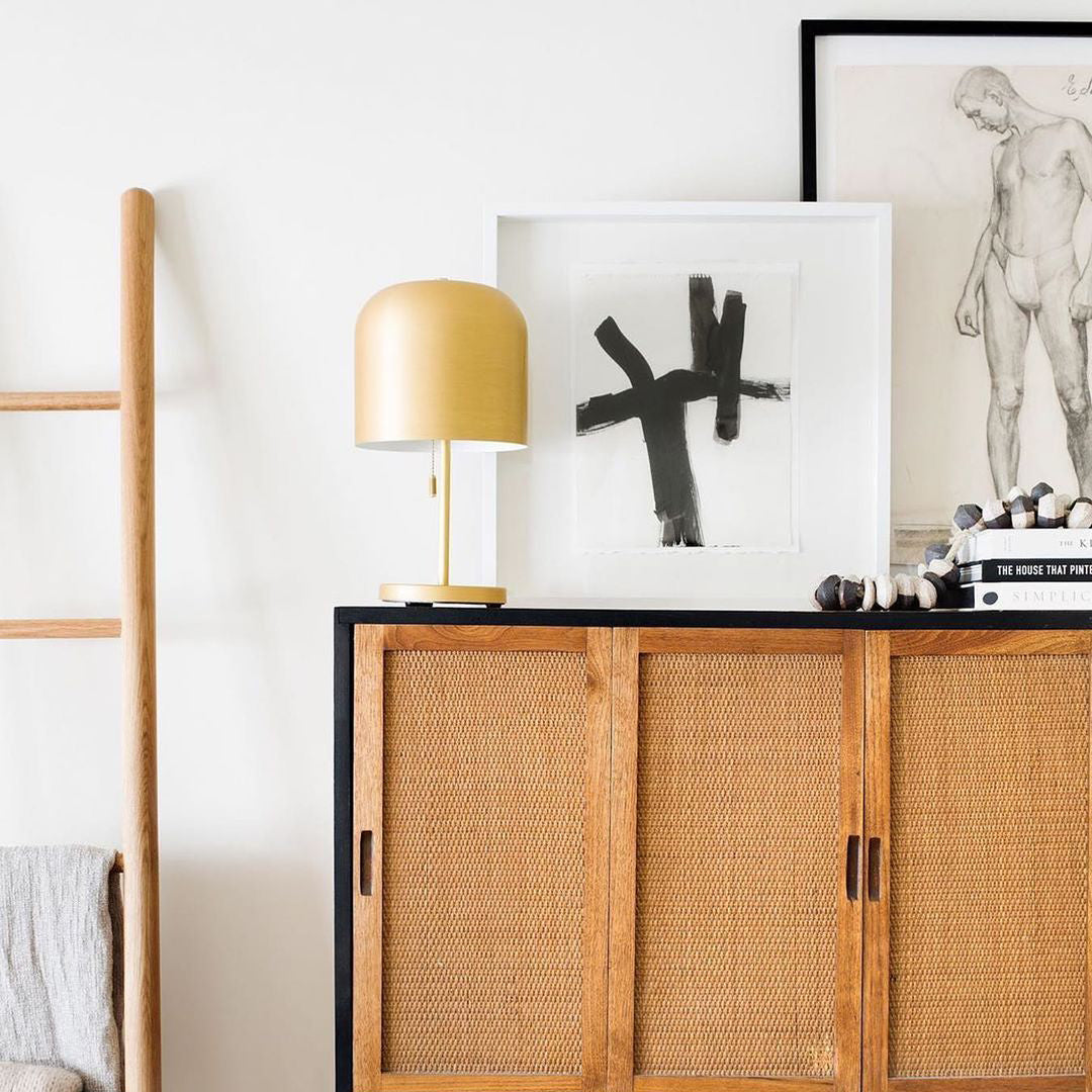 wooden cabinet with a lamp and a painting on it