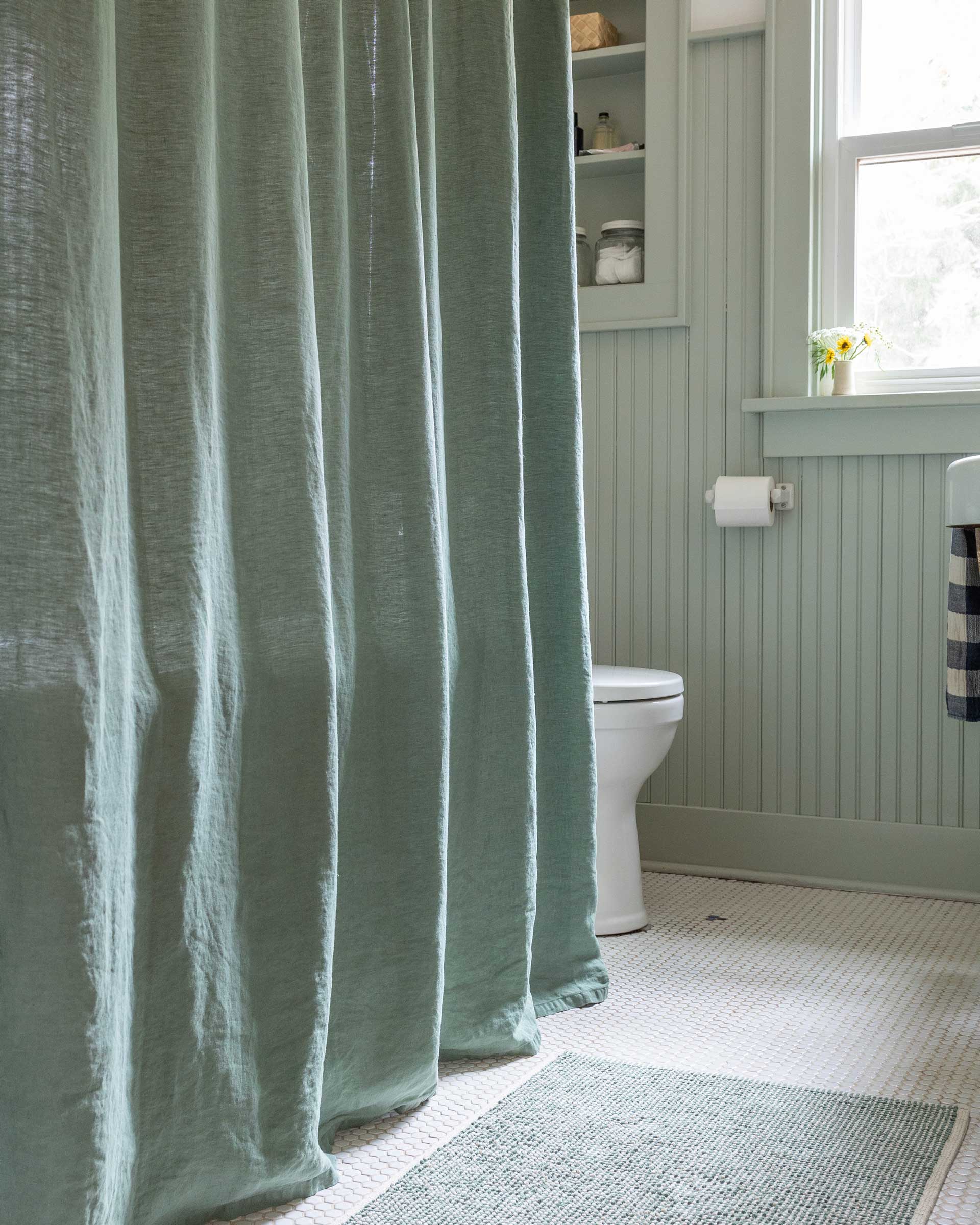 A bathroom with a green linen shower curtain.