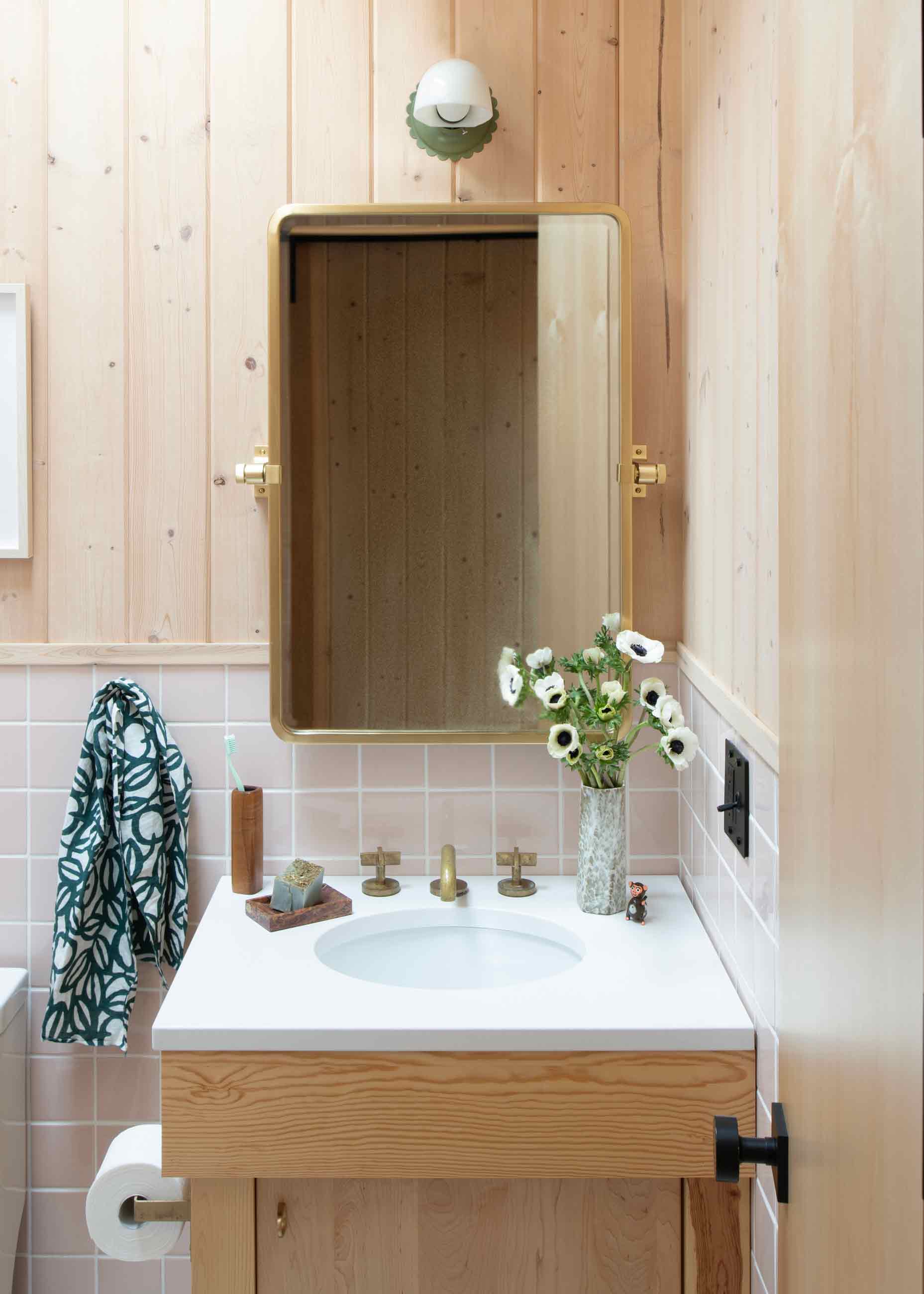 Wood walled bathroom with scalloped fixture above sink. 