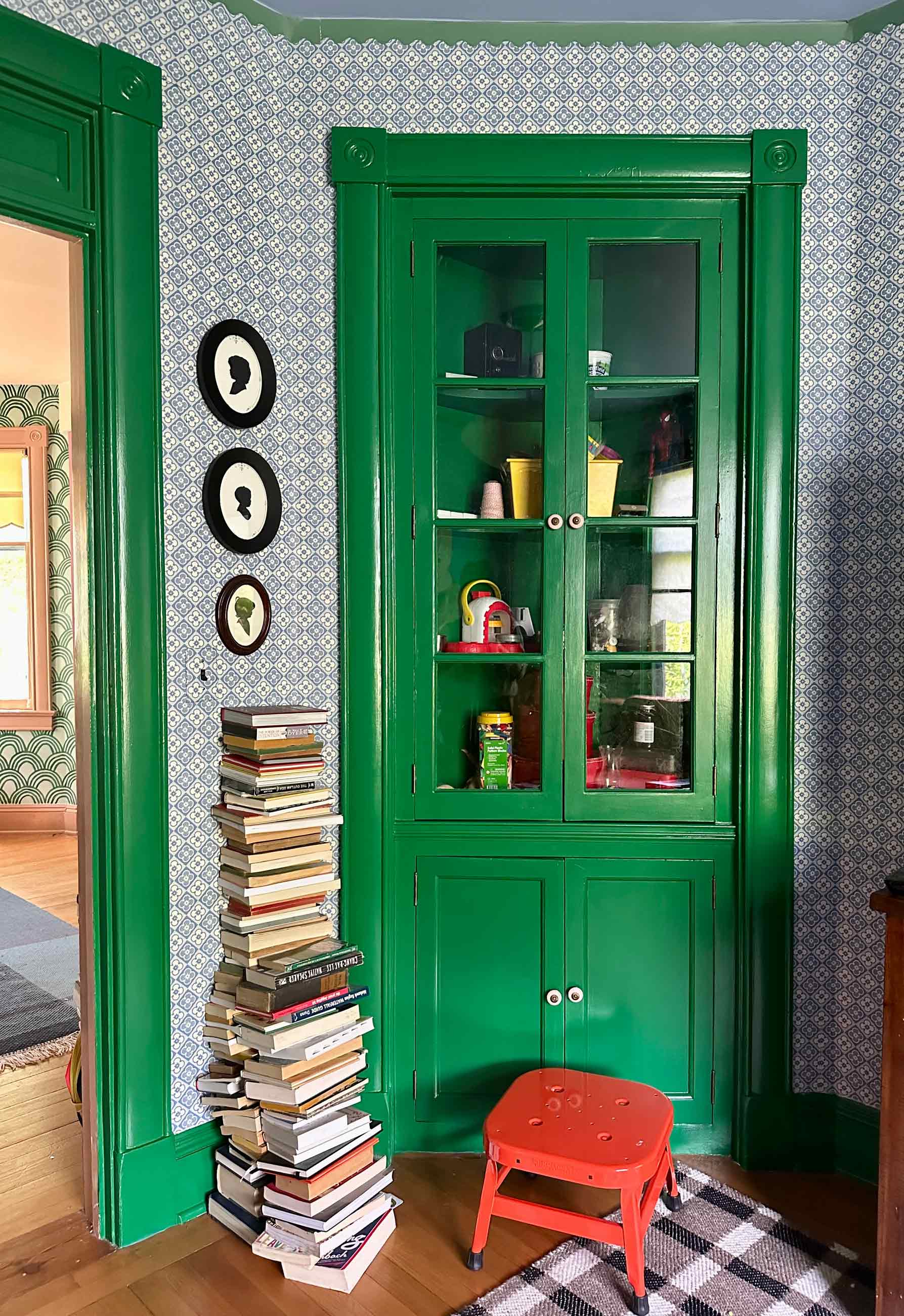 Plaid wool rug in front of brightly painted living room hutch.