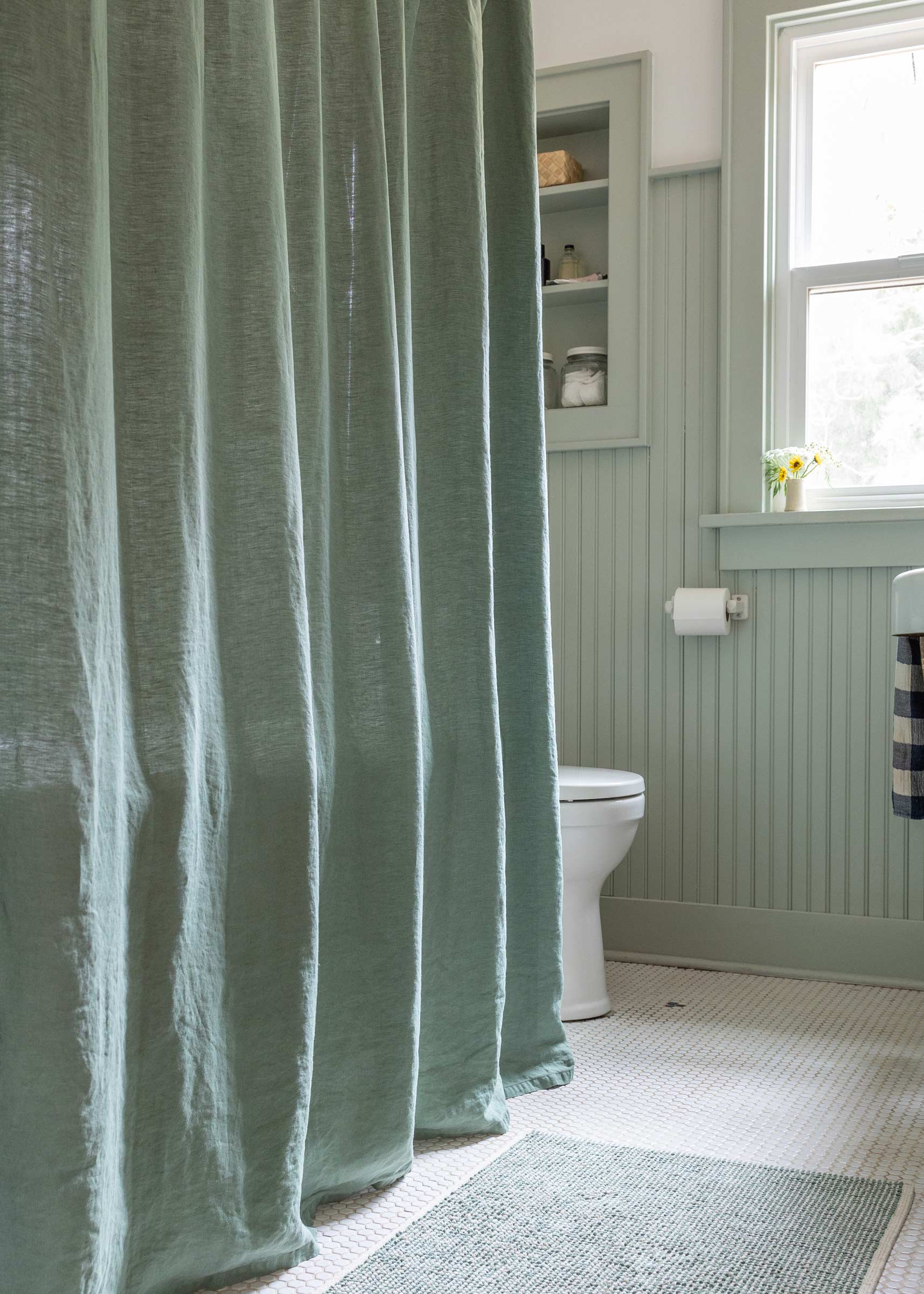 Sage linen shower curtain in a small bathroom.