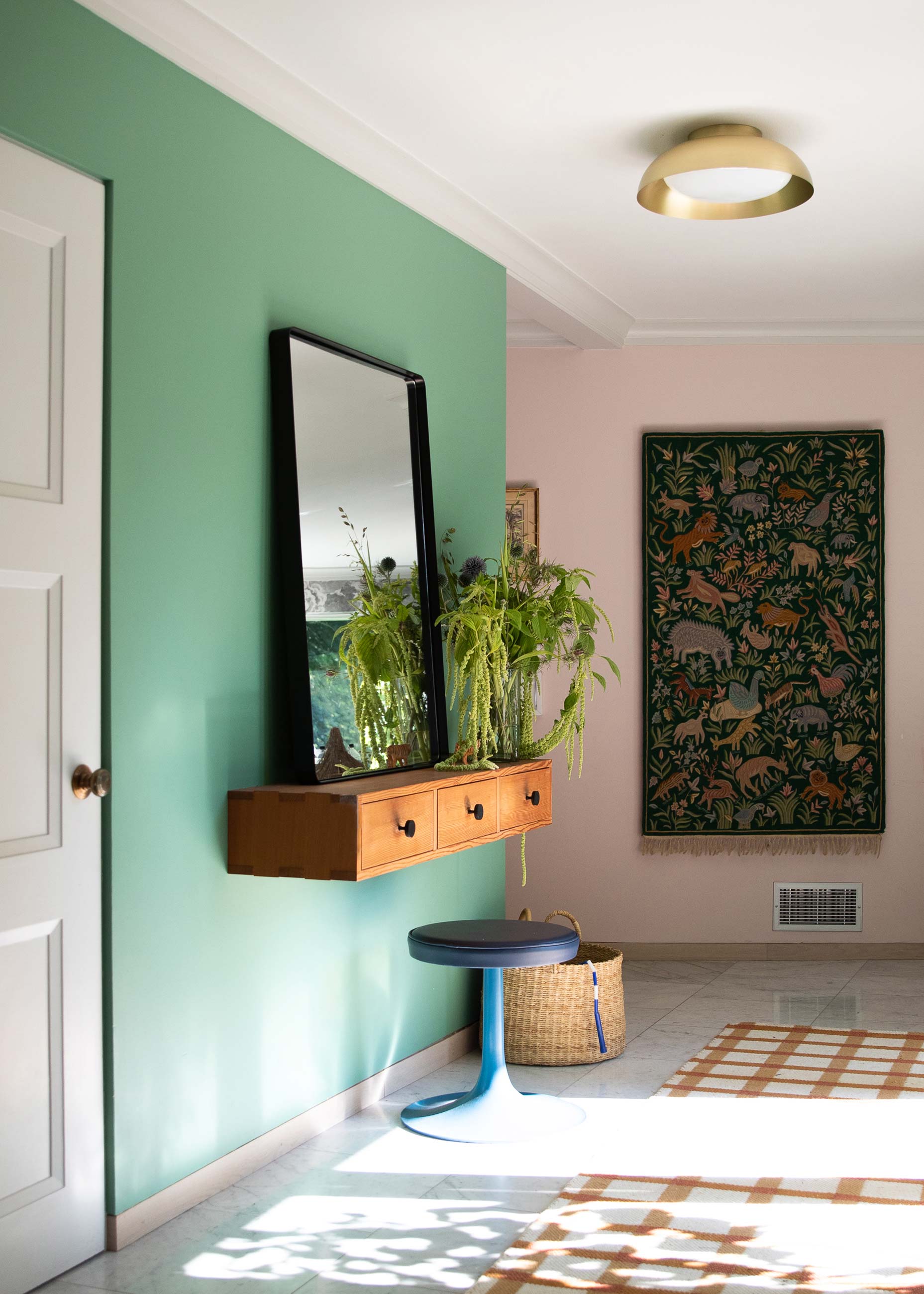 Front entryway with brass surface mount and green and pink painted walls. 