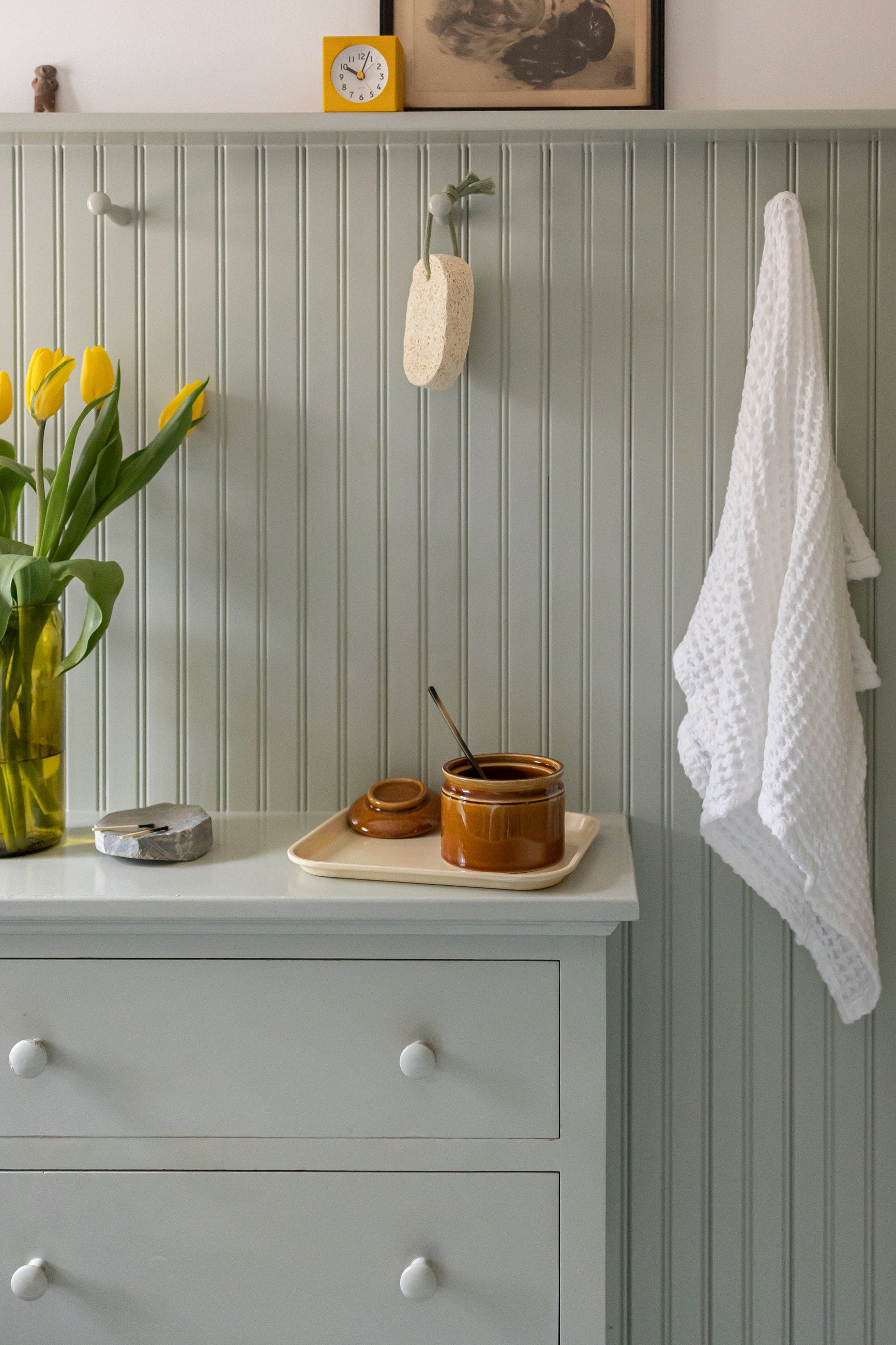 Green bead-board wall in bathroom with hooks. 