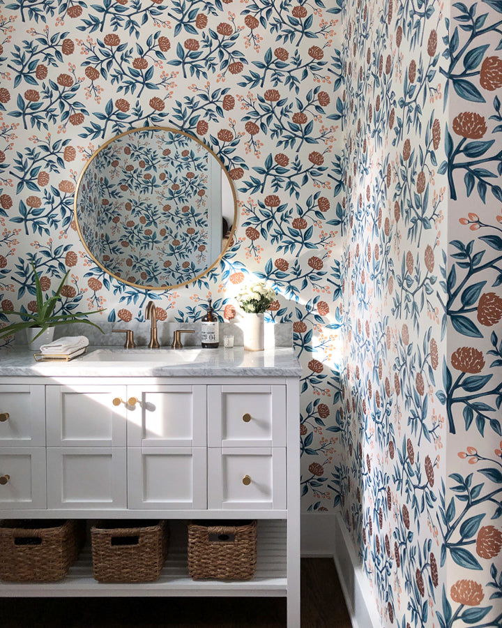 bathroom with floral wallpaper and white cabinets with wicker organizational baskets