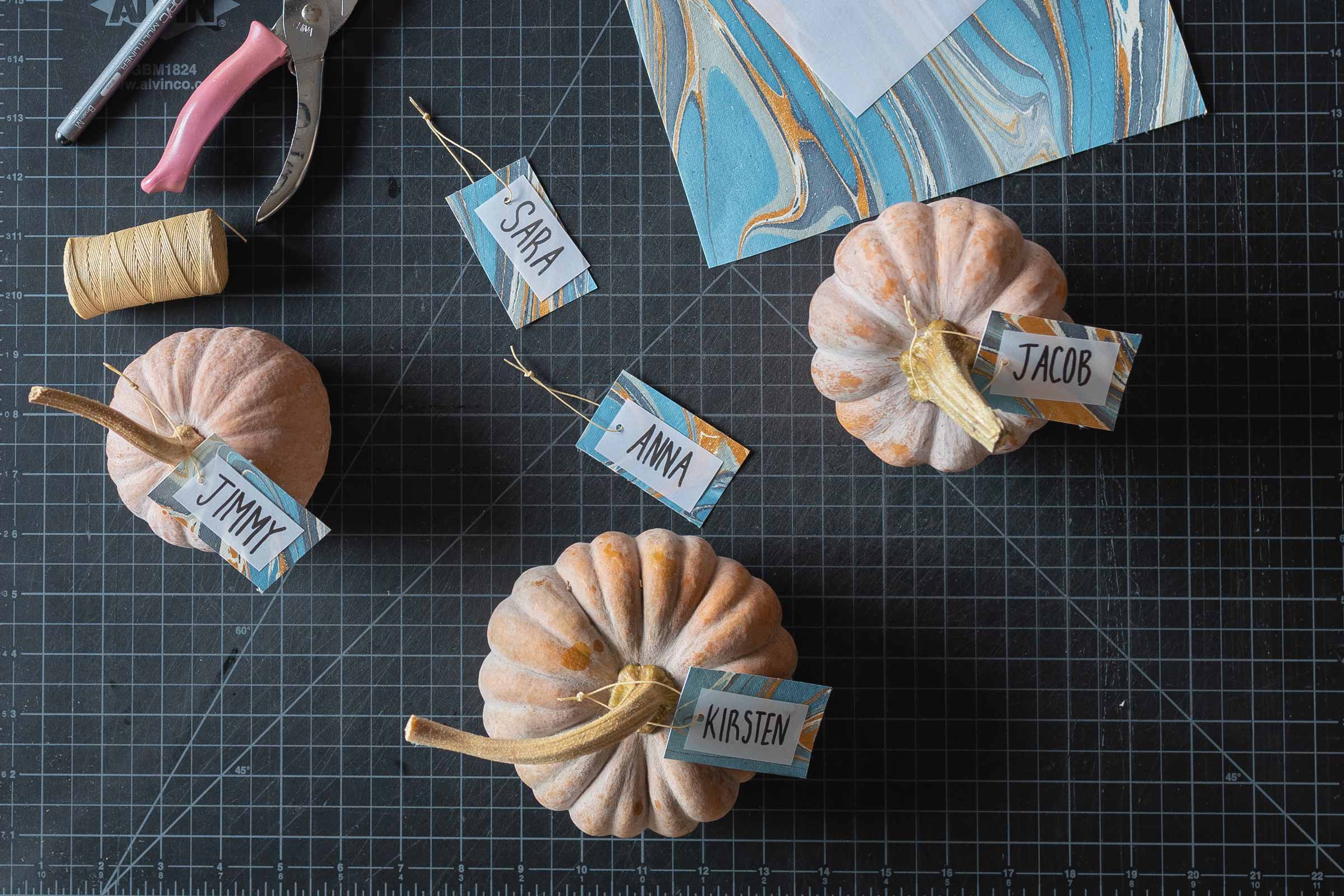 Hanging pumpkin name cards on mini pumpkins and gourds. 