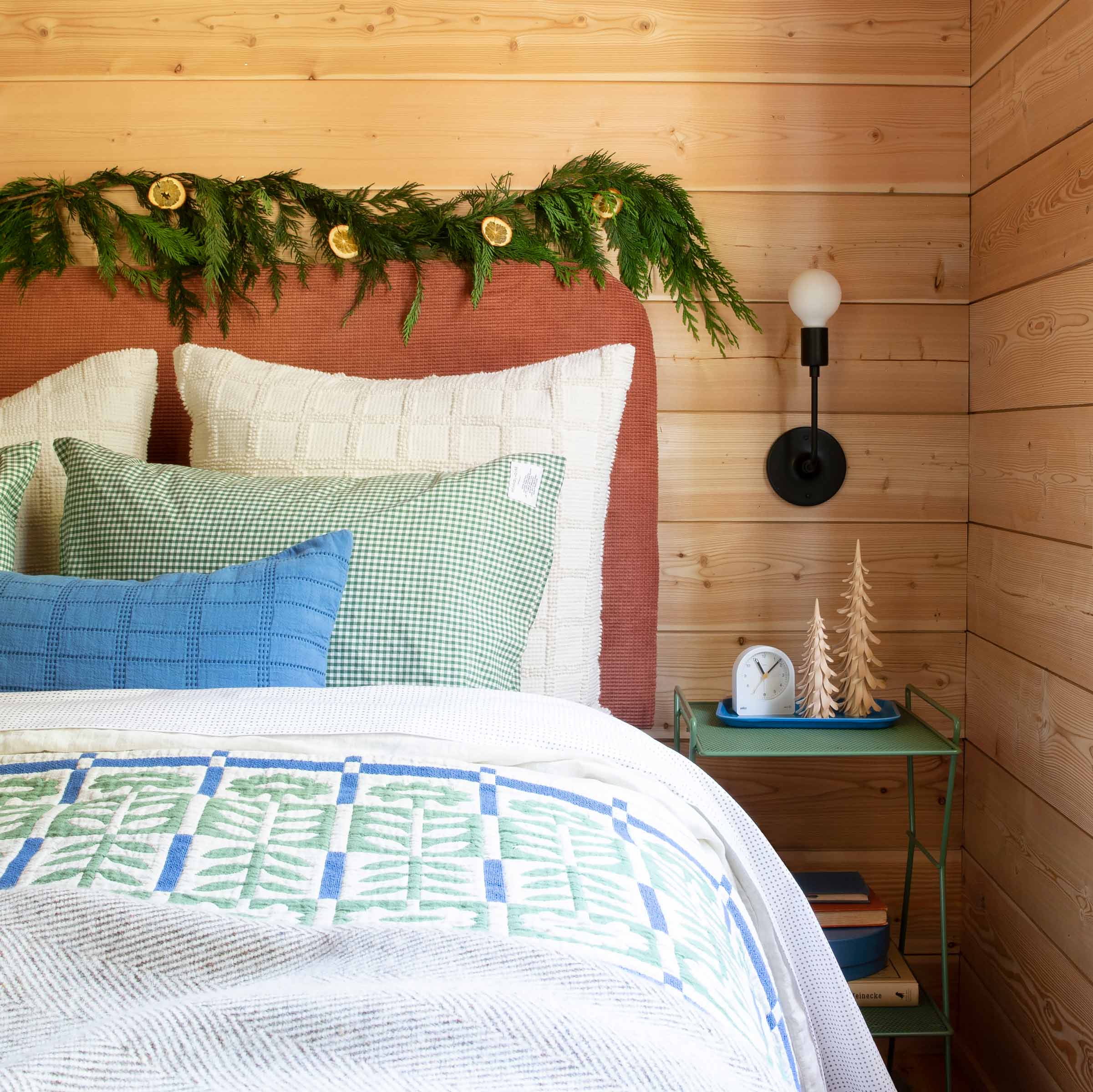 Holiday garland with dried oranges above a bed with a floral quilt.