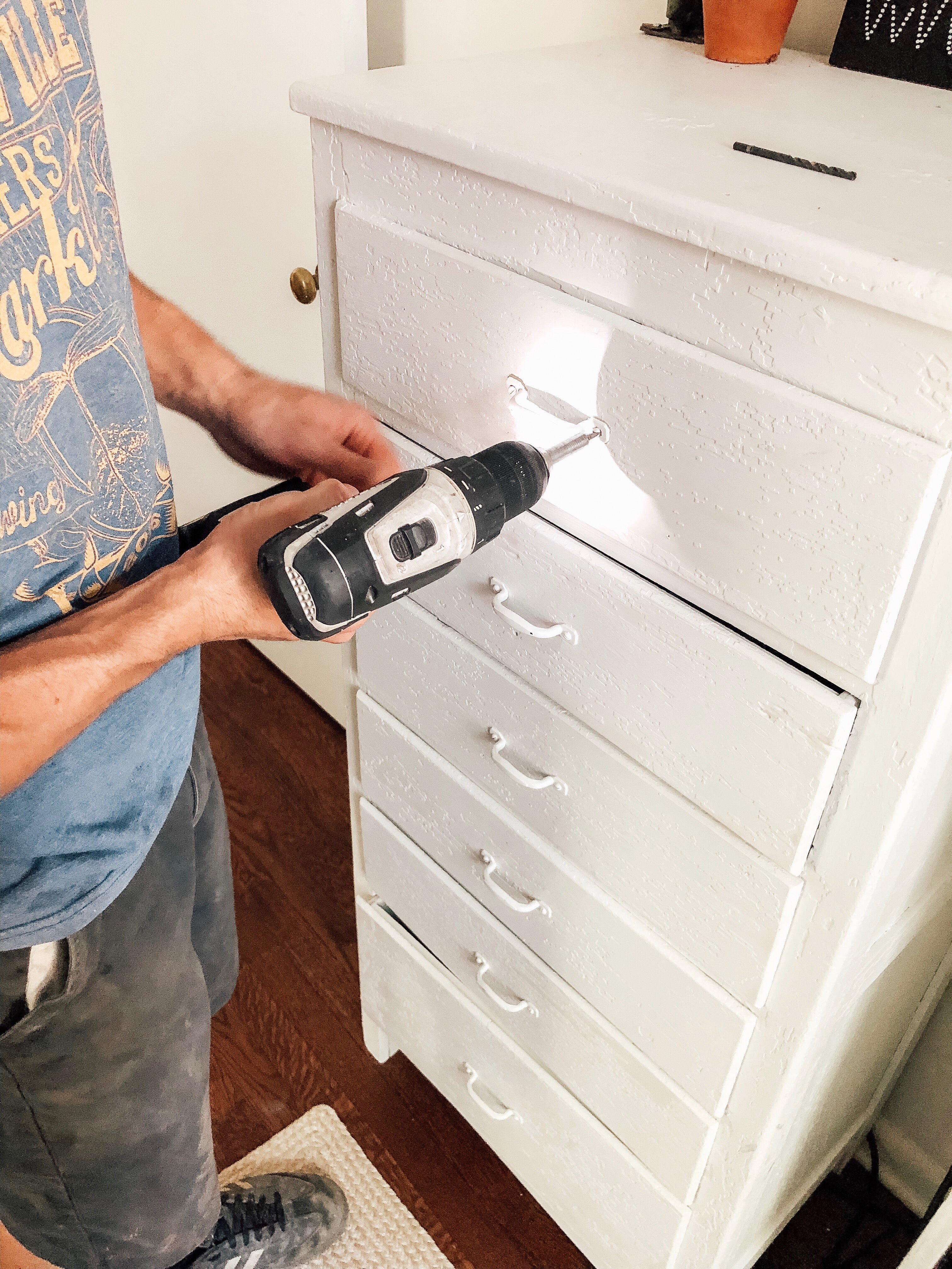 person drilling a white cabinet